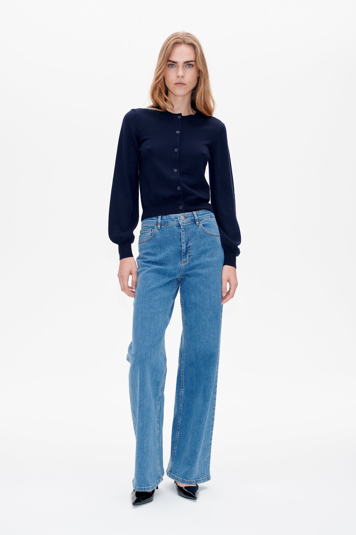 Front view of a navy button-front cardigan with full sleeves, styled with light blue wide-leg jeans.