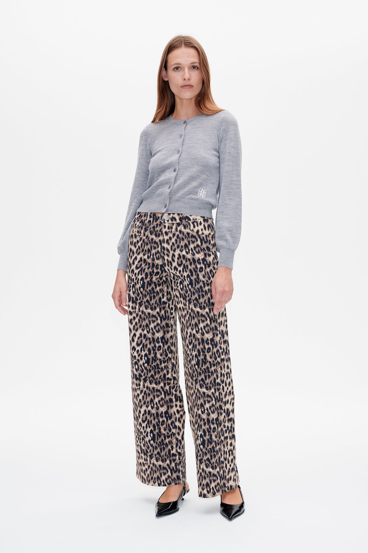 Model wearing a light grey button-front cardigan and beige-and-black leopard-print wide-leg trousers, shown from the front.