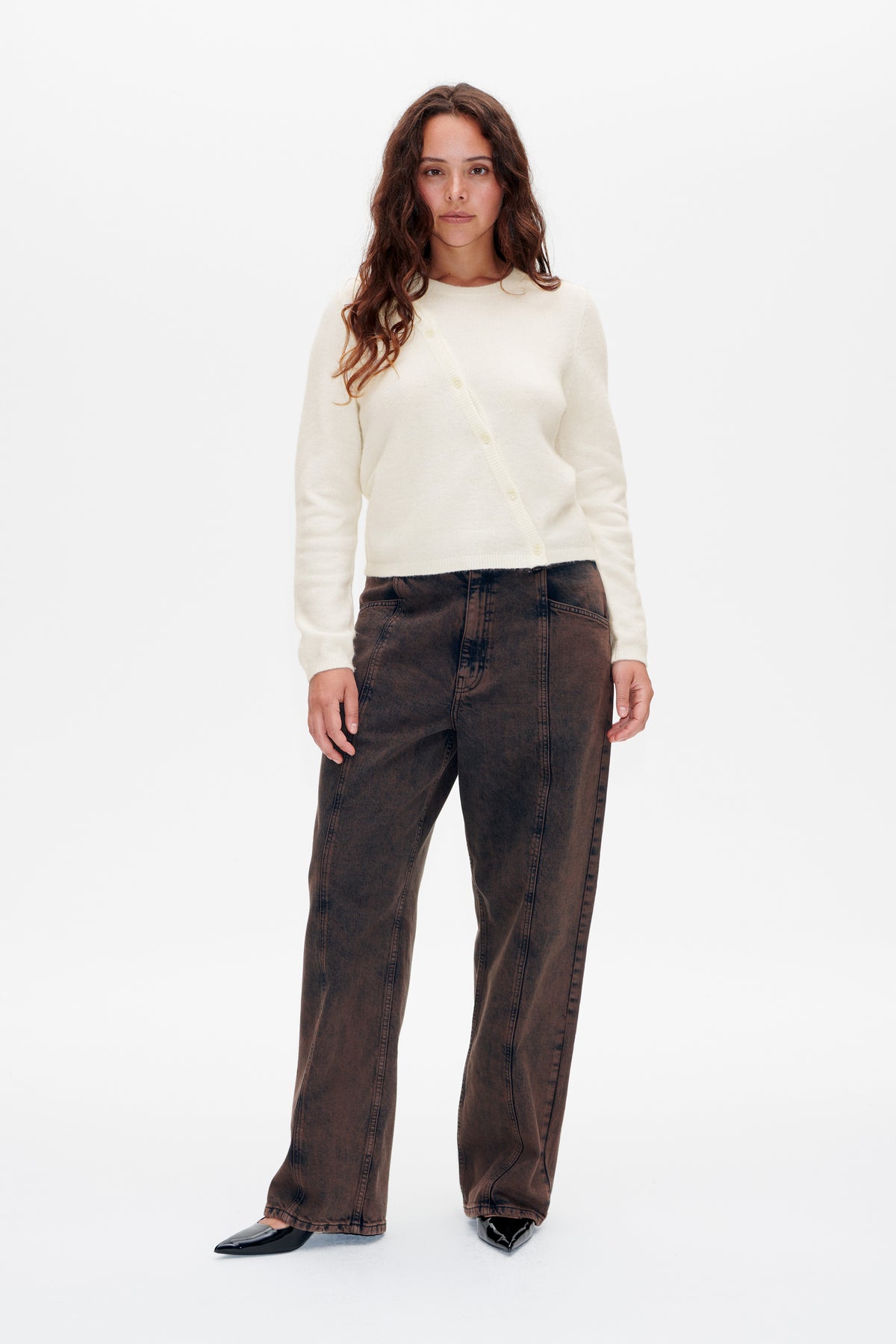 Front view of a model wearing an ivory button-front knit cardigan with dark brown washed wide-leg jeans.