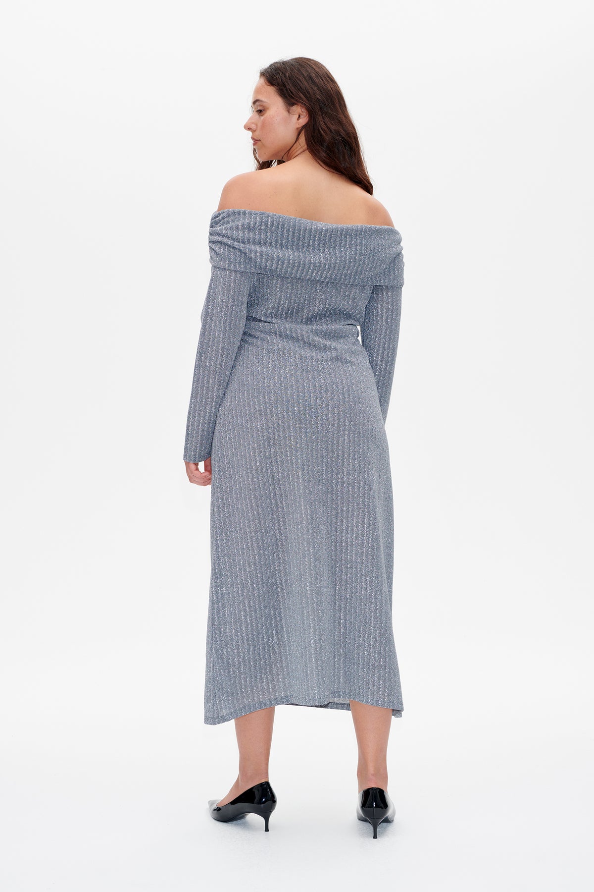 Back view of a model wearing a blue-grey shimmery ribbed midi dress with long sleeves and a folded off-the-shoulder neckline.