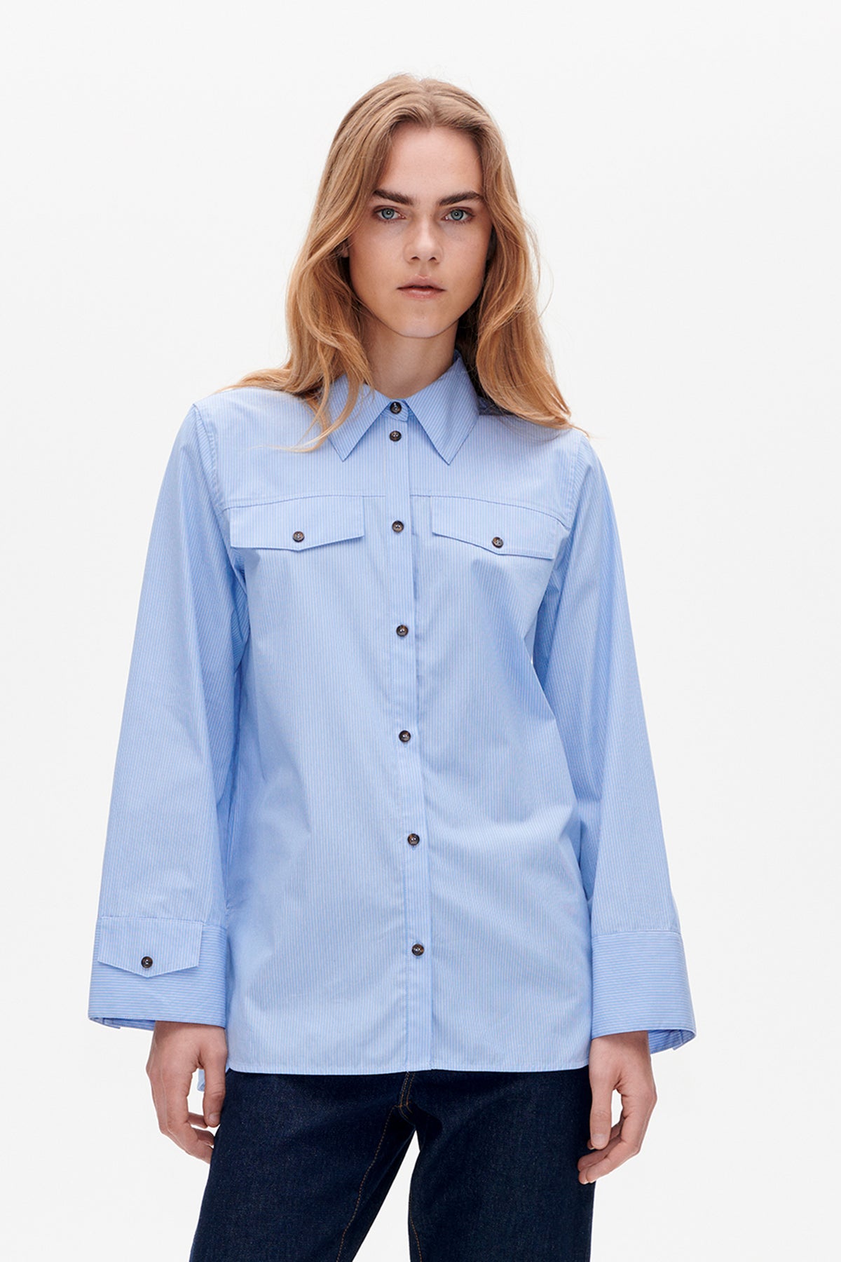 Front view of a light blue pinstriped button-up shirt with pointed collar, chest pockets and wide three-quarter sleeves.