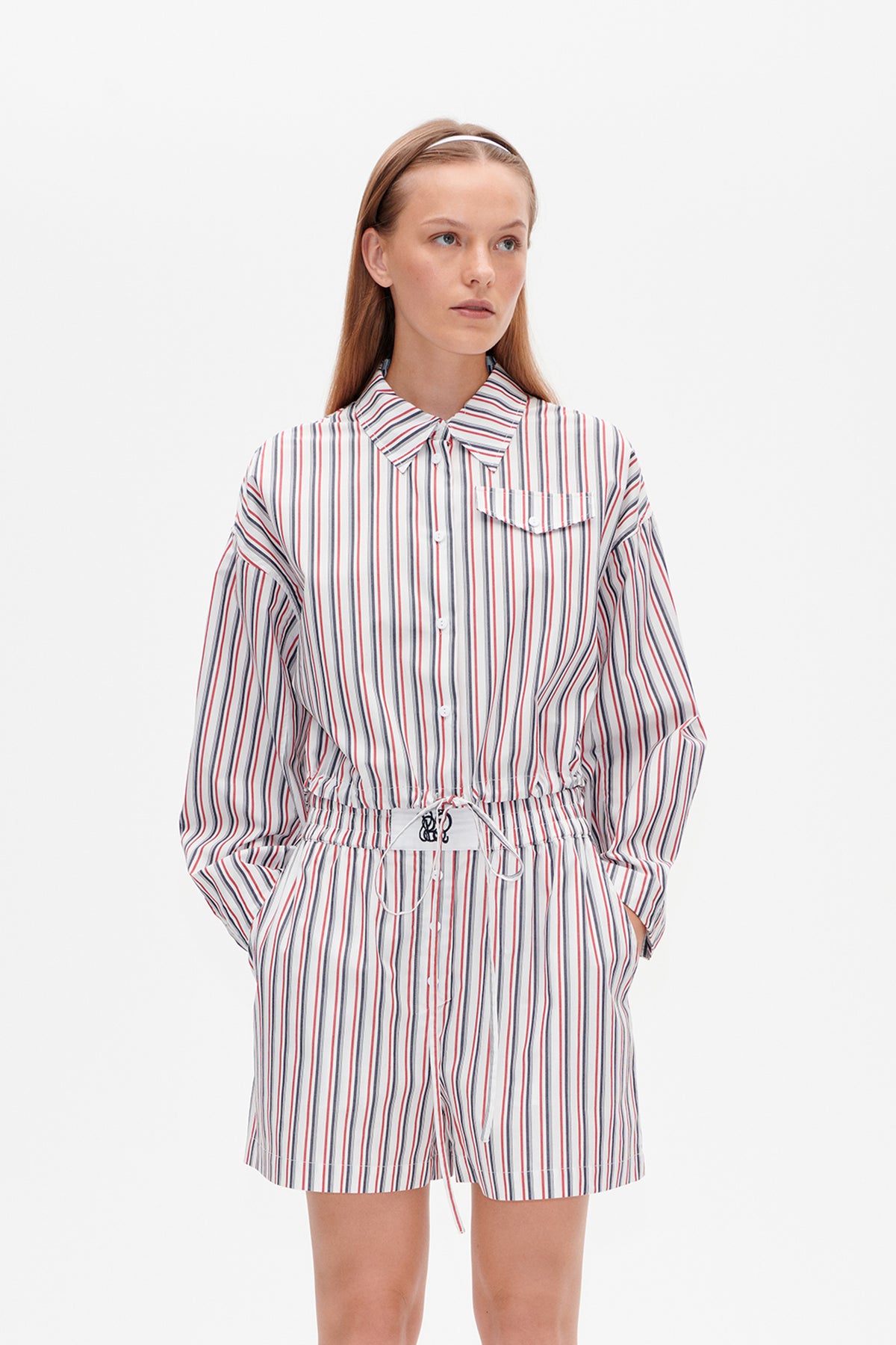 Front view of a white button-up shirt and matching shorts with red, navy and grey stripes, chest pocket and drawstring waist.