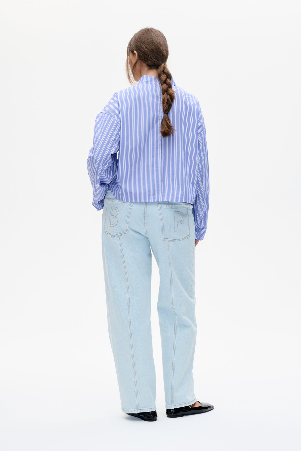 Back view of a blue-and-white vertically striped long-sleeve shirt with pale wide-leg jeans featuring outlined B and P back pockets.