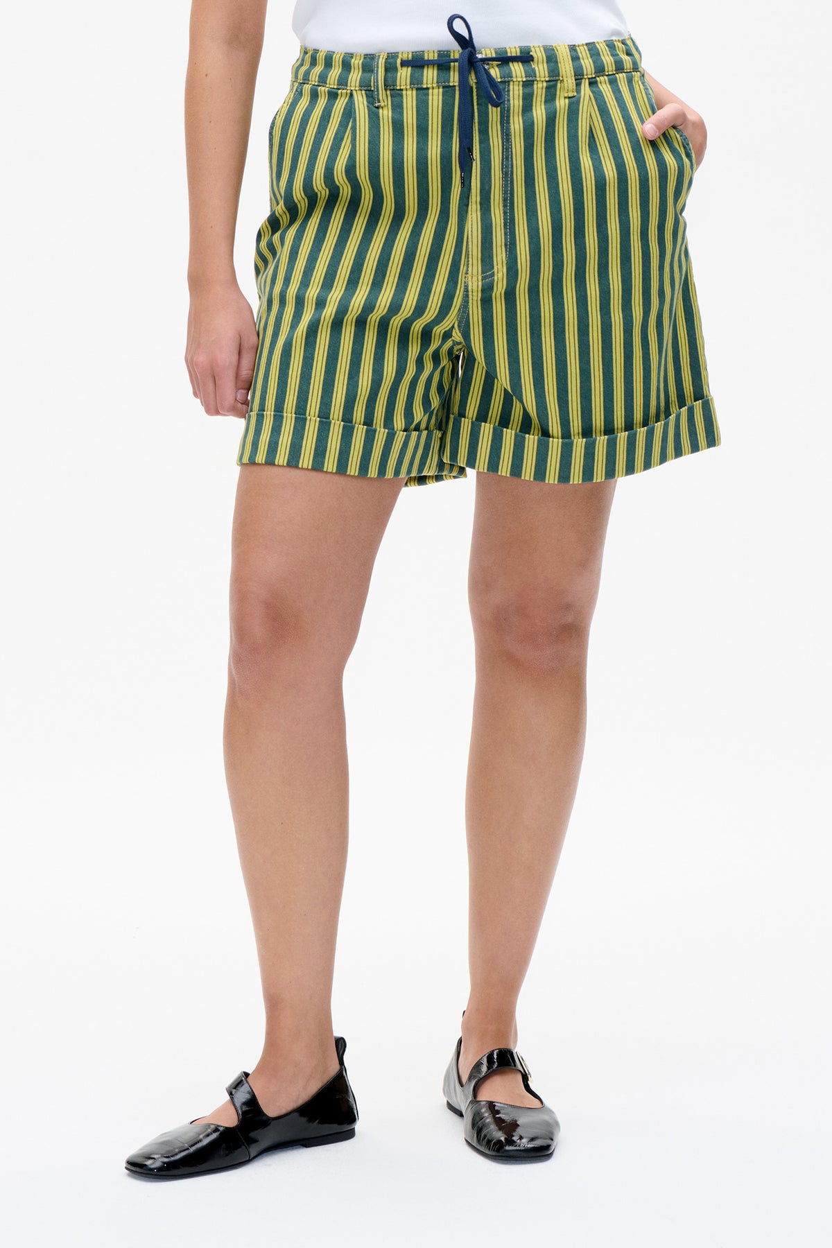 Détail avant d'un short vert à rayures verticales jaunes, taille à cordon bleu marine et larges revers.