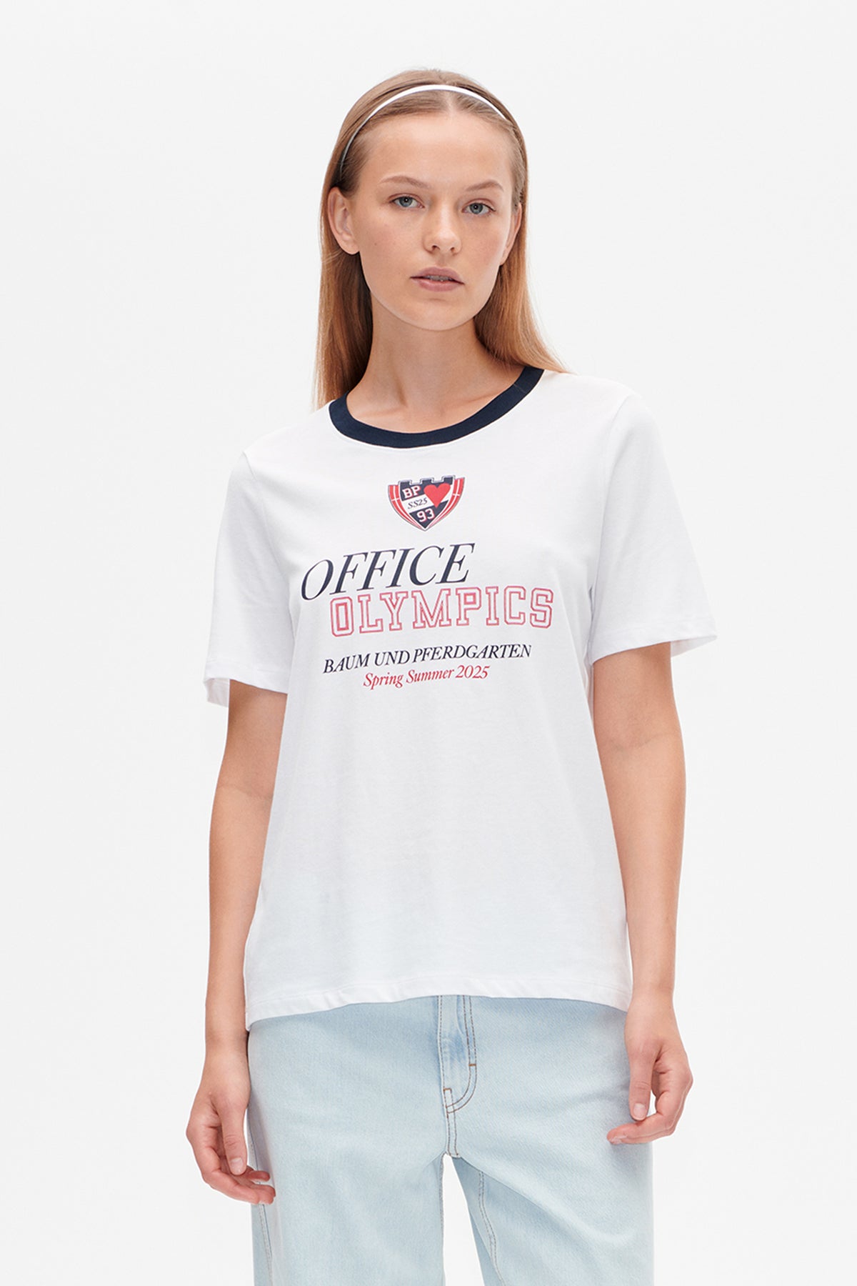 Front view of a white short-sleeved T-shirt with a navy neckline and red-and-navy “Office Olympics” chest graphic.
