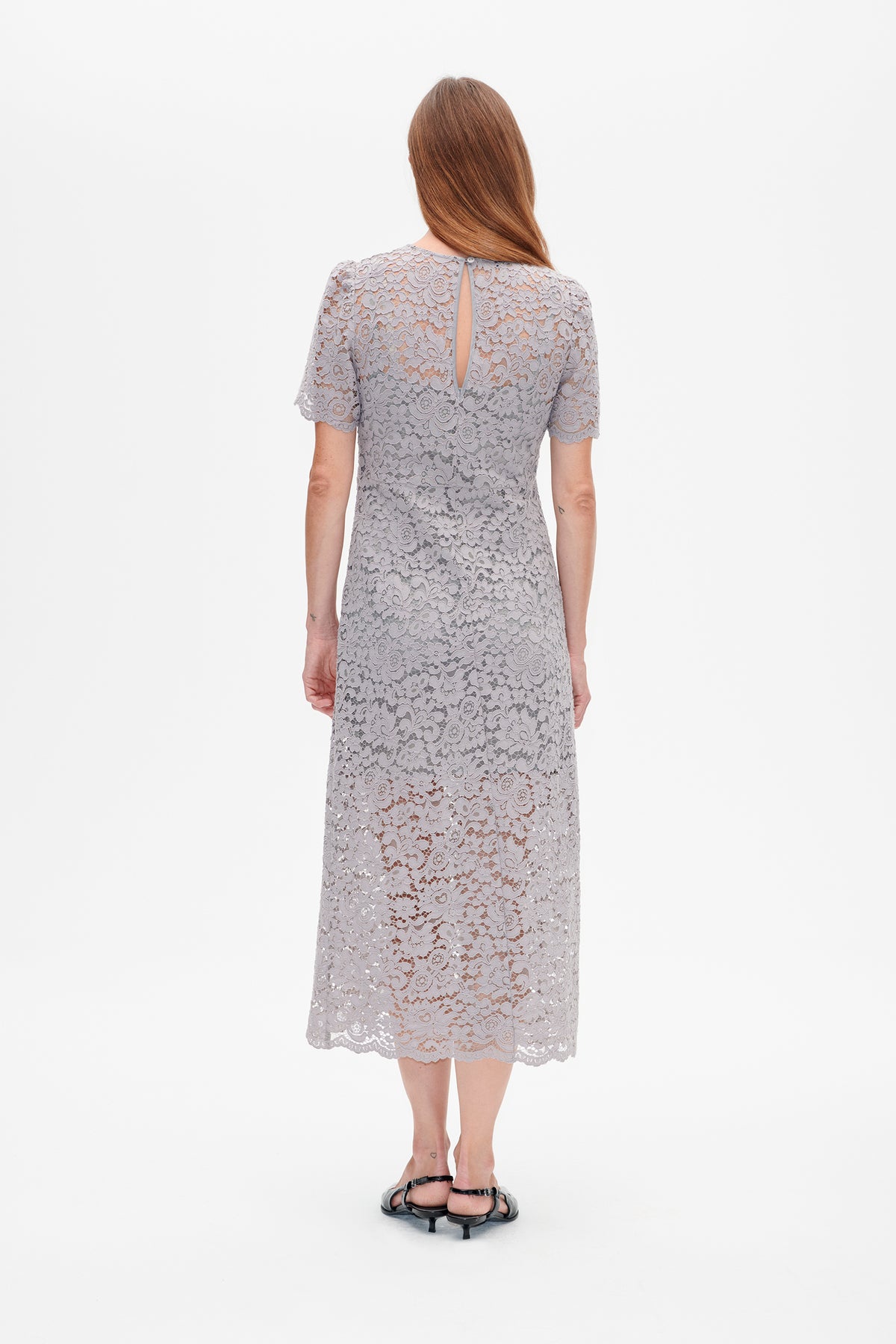 Back view of a pale grey floral lace midi dress with short sleeves, scalloped edges and a narrow keyhole opening.