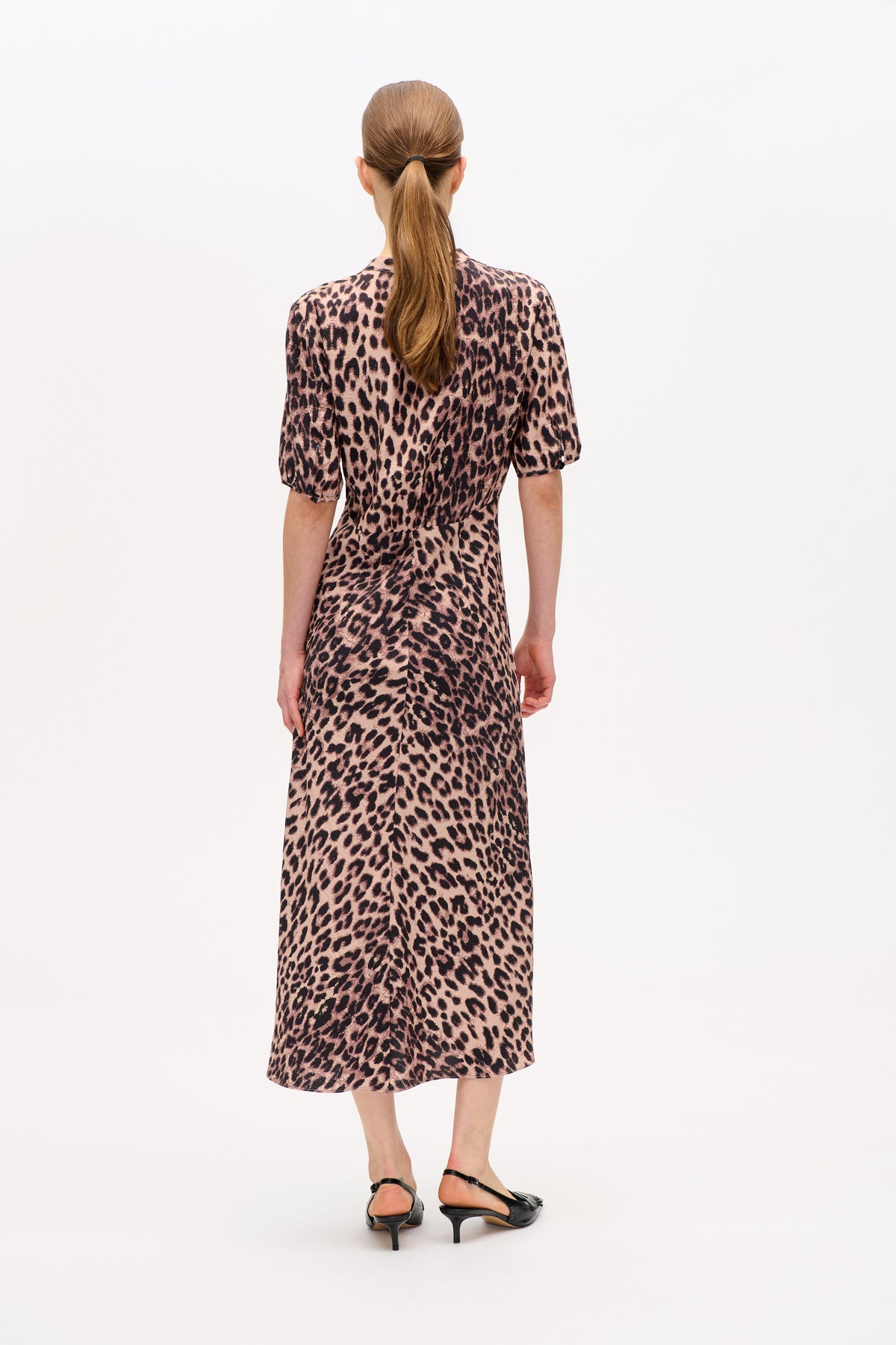 Back view of a model wearing a pink and black leopard-print knee-length dress with short puff sleeves.