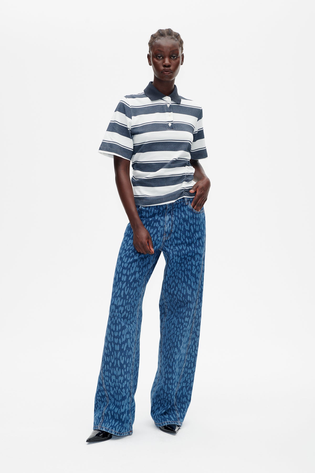 Mannequin portant un polo à manches courtes rayé bleu marine et blanc, associé à un jean large bleu à motif, vue de face.