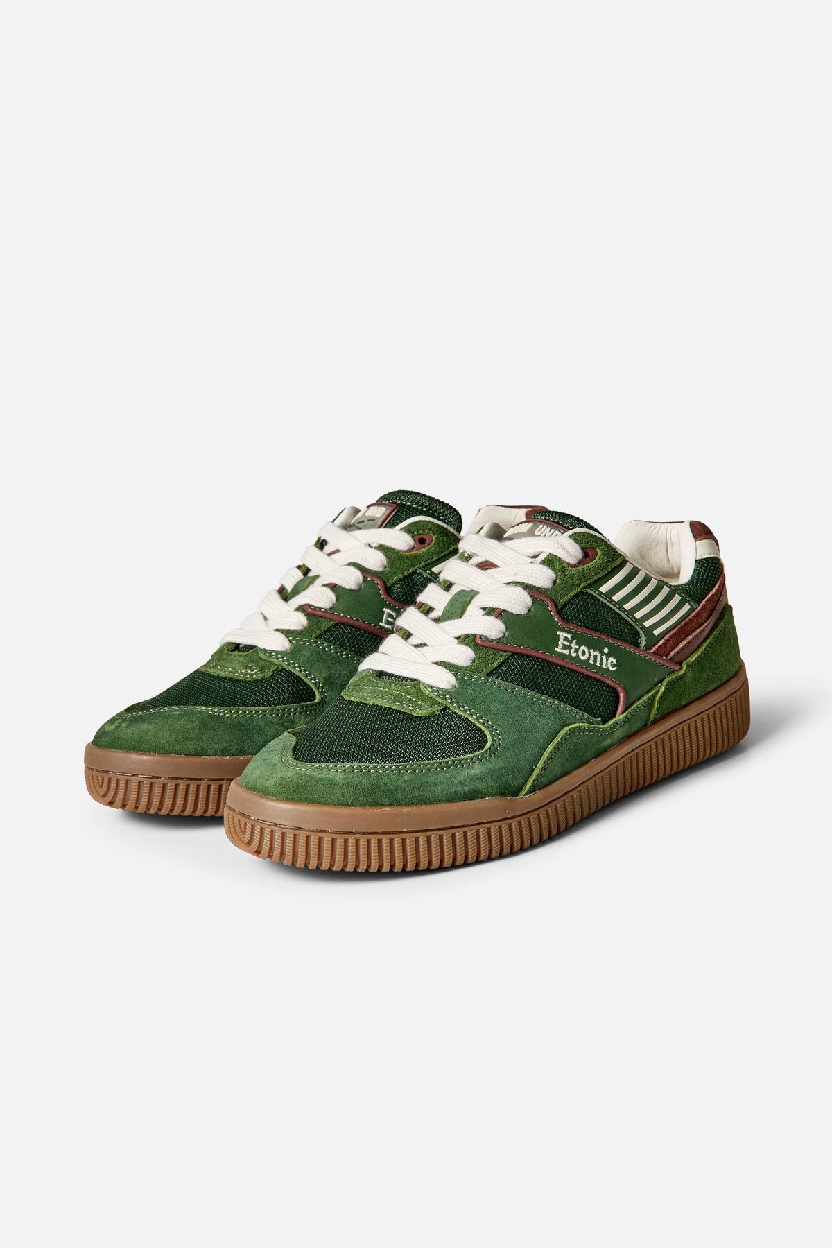 Pair of dark green low-top sneakers with white laces, contrast paneling, cream stripes and brown rubber soles, shown from the front and side.