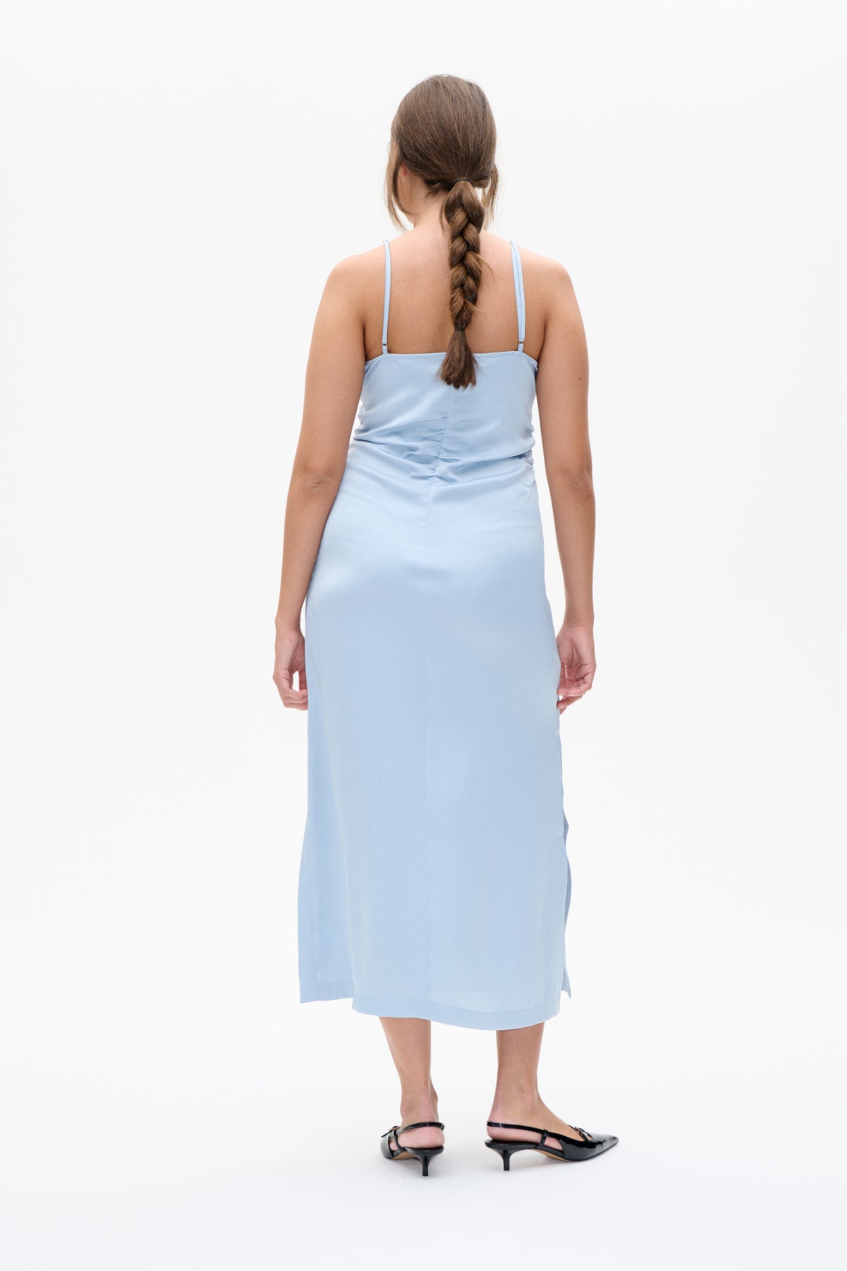 Back view of a pale blue midi dress with thin adjustable straps and gathered fabric at the waist.