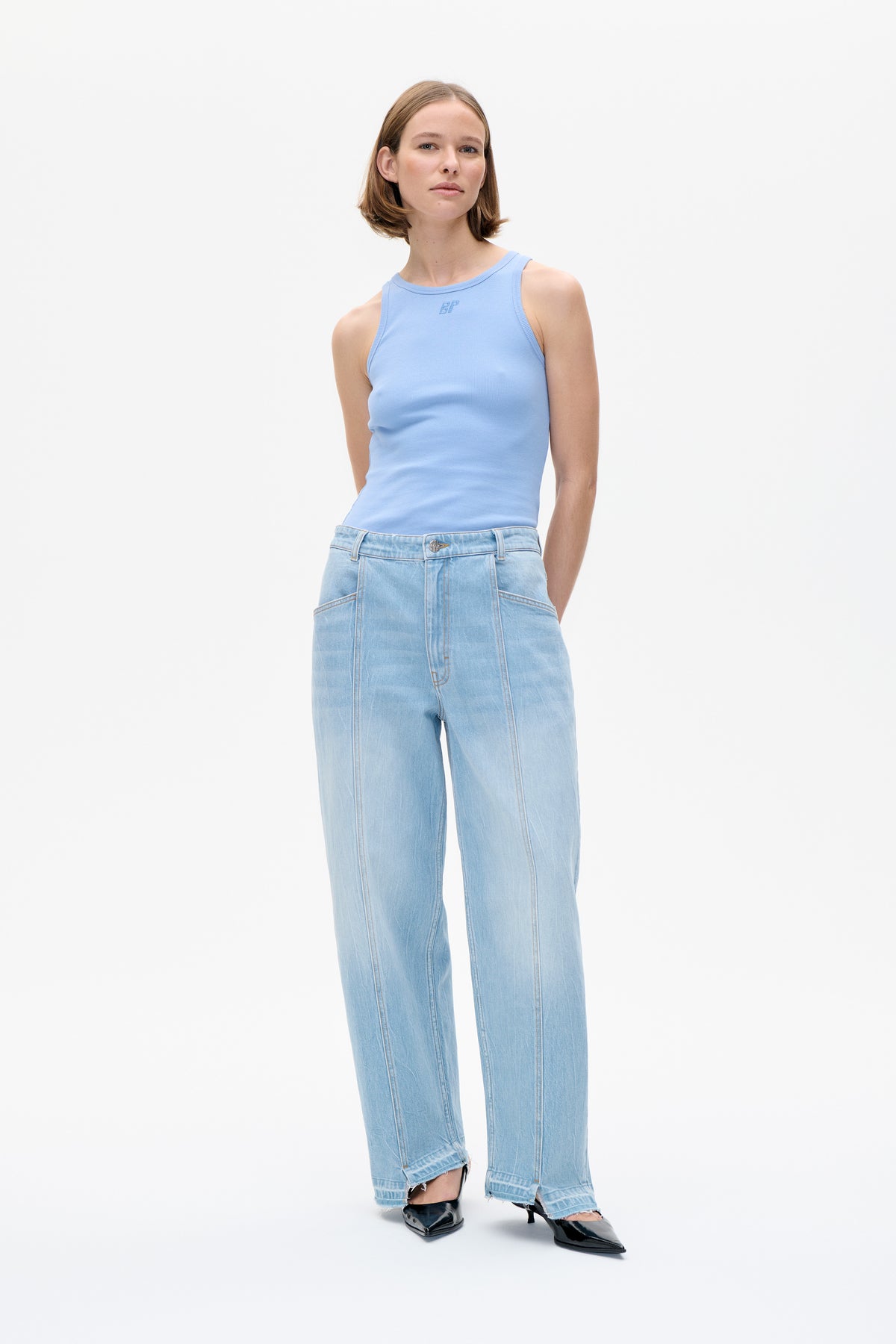 Model trägt ein hellblaues, ärmelloses, geripptes Top mit kleinem ton-in-ton BP-Logo auf der Brust und eine Jeans in heller Waschung, weit geschnitten, mit ausgefransten Säumen.