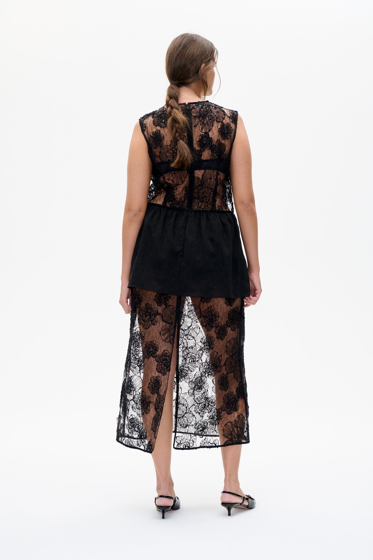 Back view of a black sleeveless dress with sheer floral lace panels and an opaque black overlay at the hips.