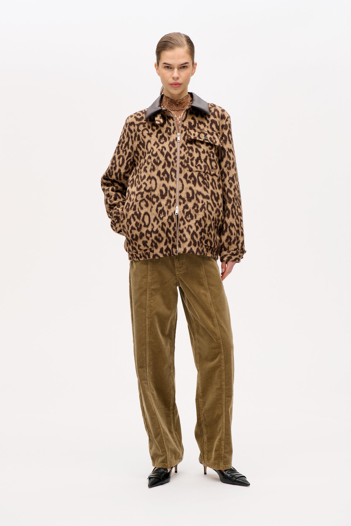 Model wearing a tan and dark brown leopard-print zip-front jacket with a black collar and olive corduroy trousers.