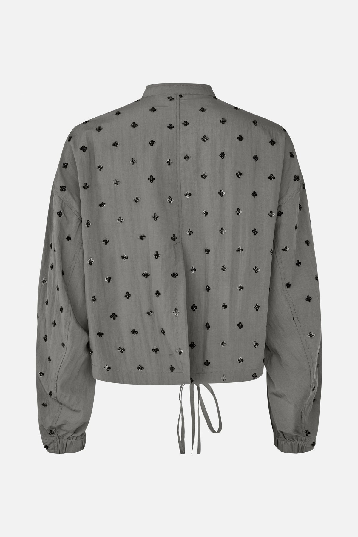 Rückansicht einer grauen, langärmeligen Bluse mit Kragen, verstreuten schwarzen Blumenverzierungen, elastischen Bündchen und Kordelzug am Saum.