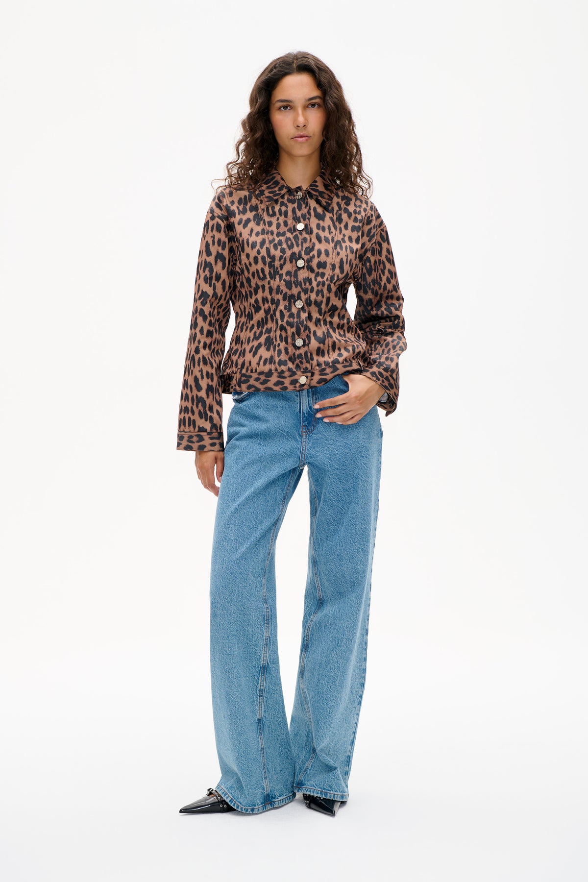 Model wearing a brown and black leopard-print button-front jacket with a pointed collar and blue wide-leg jeans.