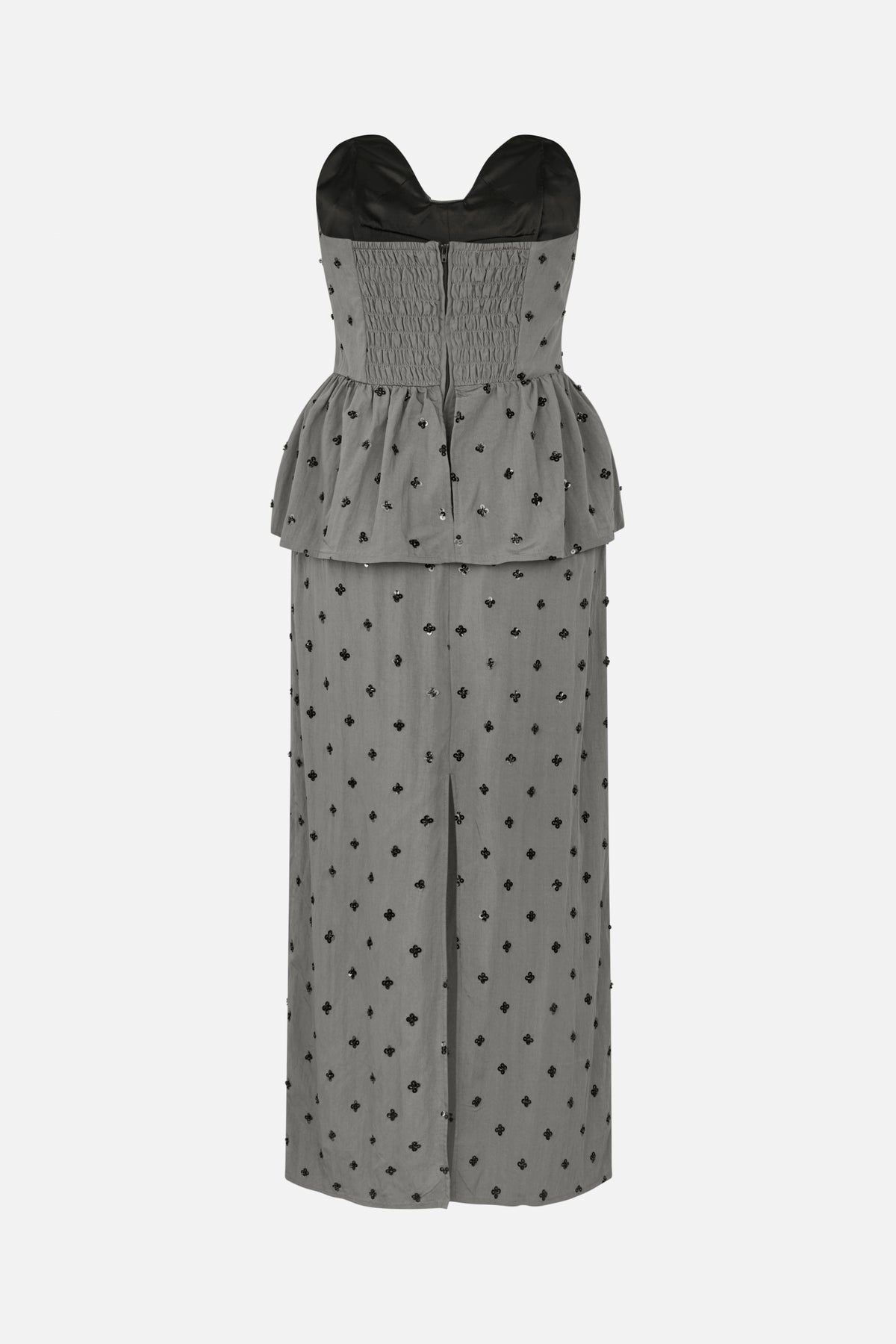 Vorderansicht eines grauen trägerlosen Maxikleids mit gerafftem Oberteil, Peplum-Taille, schwarzen Blumenapplikationen und einem vorderen Schlitz.
