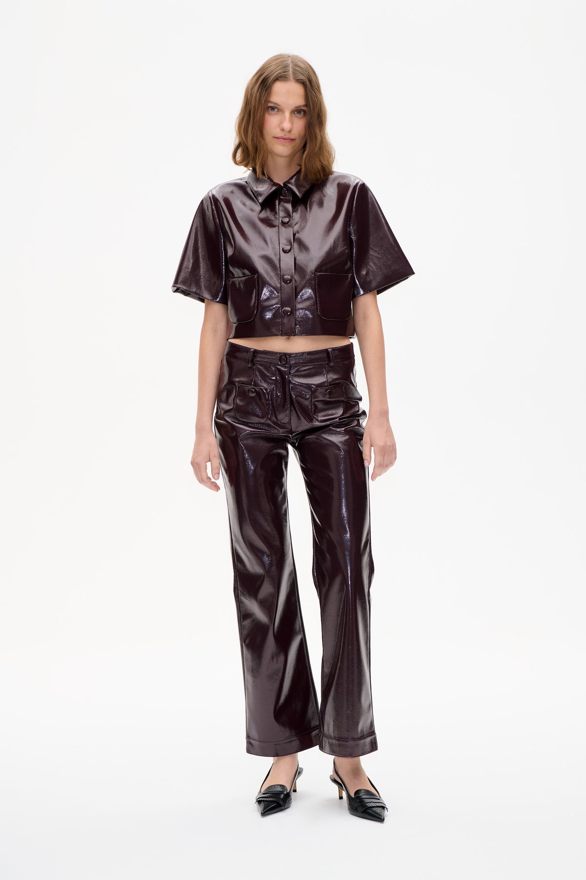 Model wearing a glossy dark burgundy button-front shirt with short sleeves and matching wide-leg trousers, shown from the front.