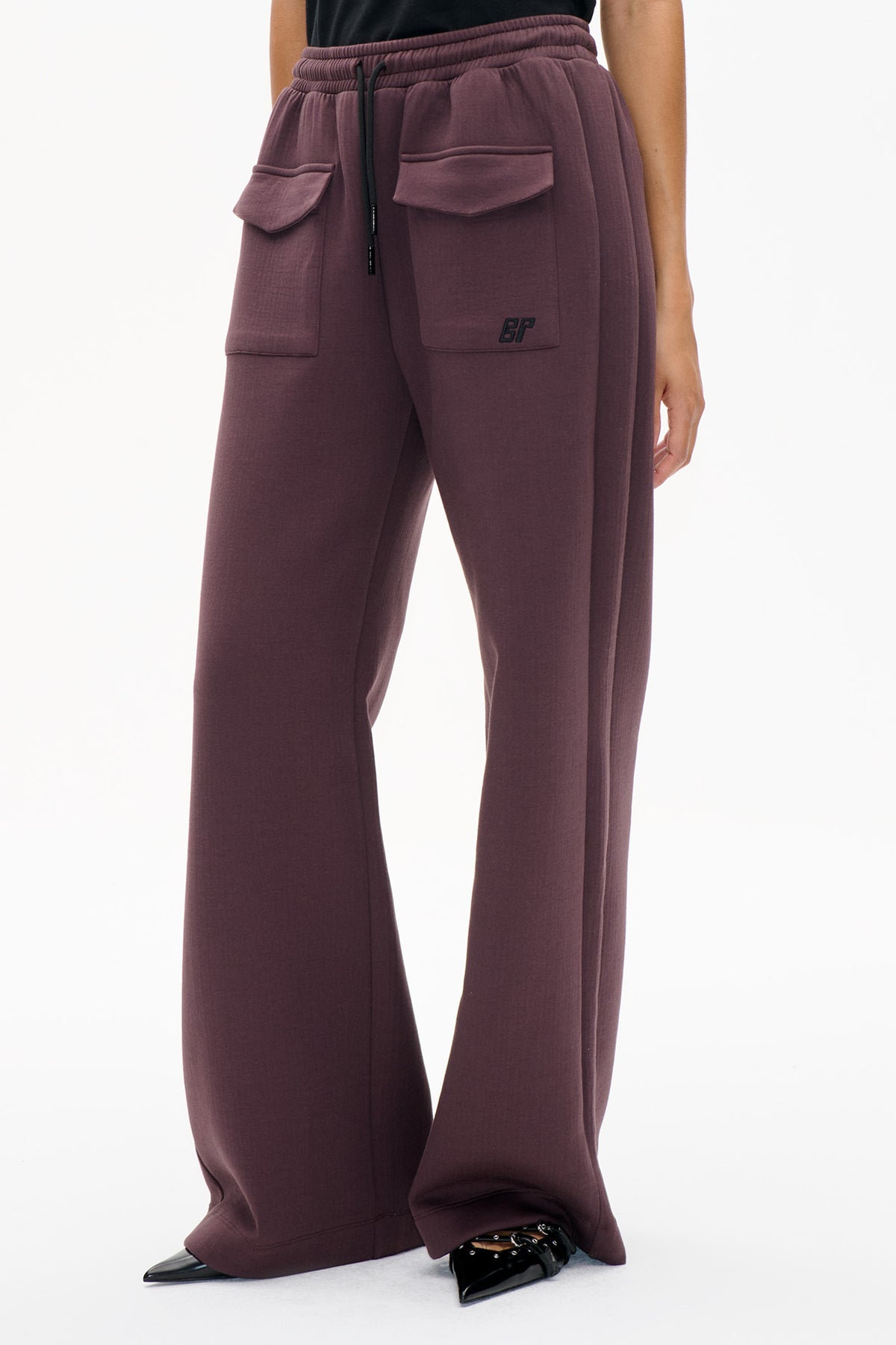 Detail van de voorkant van pruimkleurige sweatpants met wijd uitlopende pijpen, een geribde tailleband met trekkoord, grote klepzakken en een klein geborduurd BP-logo.