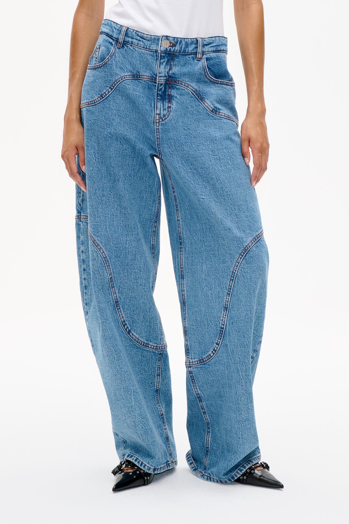 Front detail of light blue washed jeans with curved panel seams, contrast stitching, belt loops and a button closure.