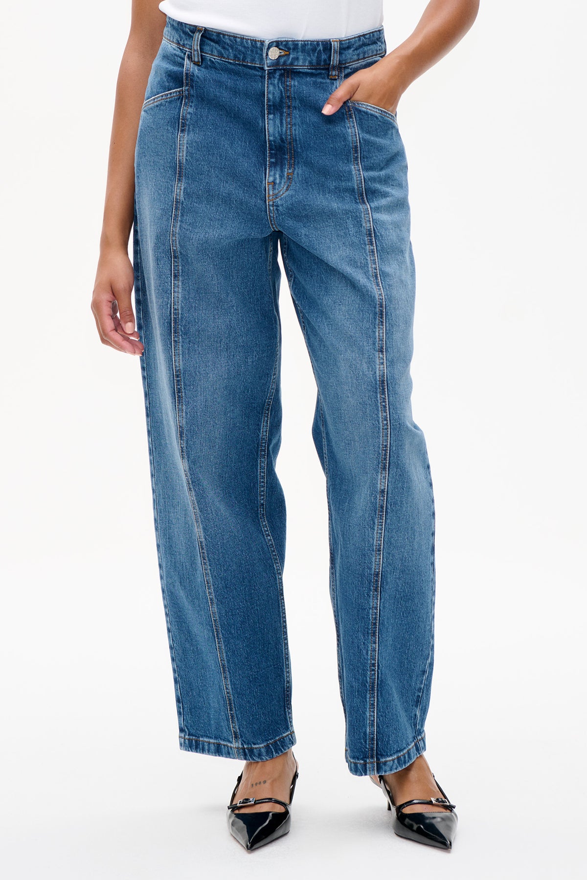Close-up front view of blue wide-leg jeans with contrasting panel seams, orange topstitching, and a buttoned waistband.