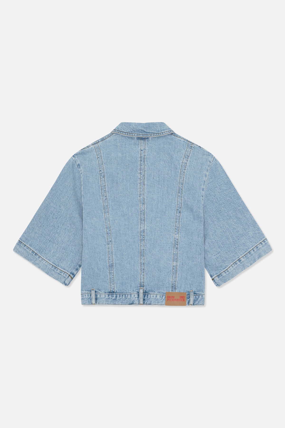 Back view of a light-wash denim jacket with short sleeves, contrast stitching and a Baum und Pferdgarten patch at the hem.
