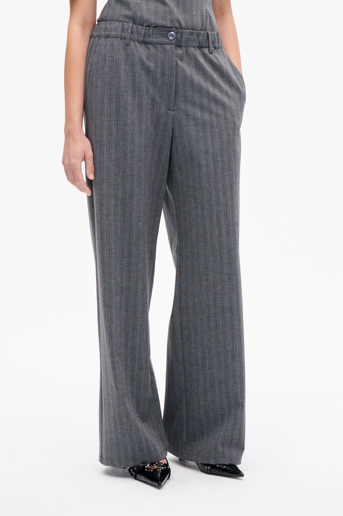 Detail der Vorderseite einer anthrazitgrauen Hose mit weitem Bein, feinen Längsstreifen, Gürtelschlaufen und geknöpftem Bund.