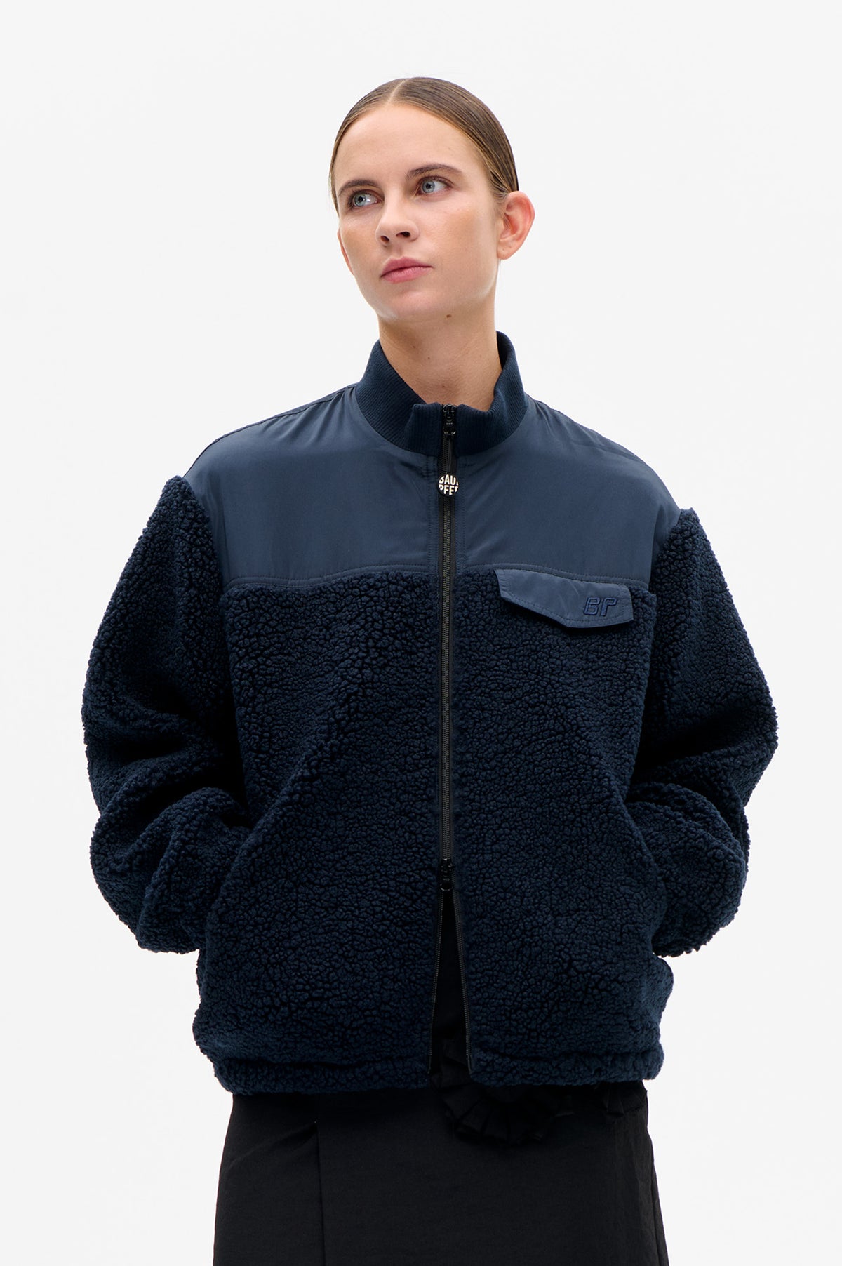 Front view of a navy sherpa jacket with smooth blue chest panels, a zip front, ribbed stand collar and flap pocket.