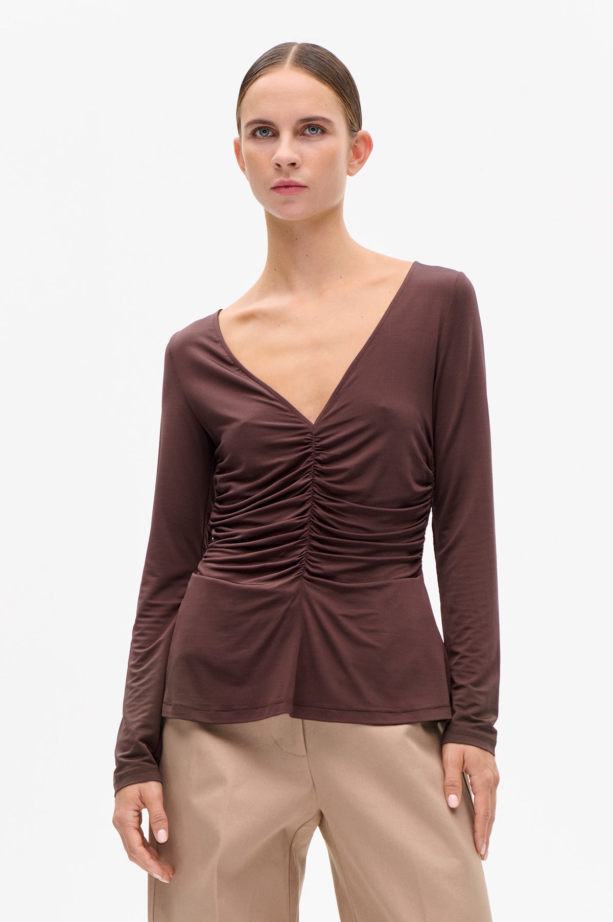 Front view of a mauve-brown long-sleeved top with a deep V neckline and gathered ruching down the centre front.
