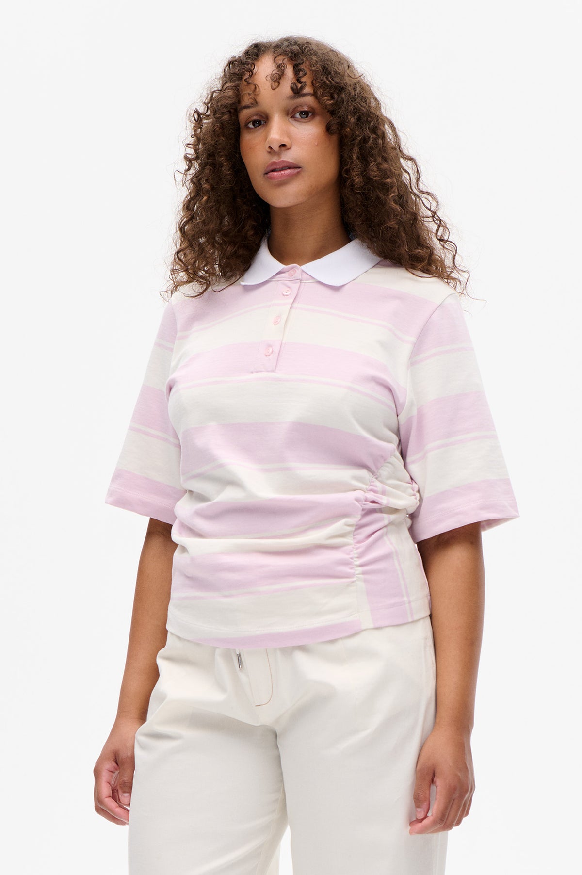 Front view of a short-sleeved polo shirt with broad pale pink and cream stripes, a white collar, and a button placket.