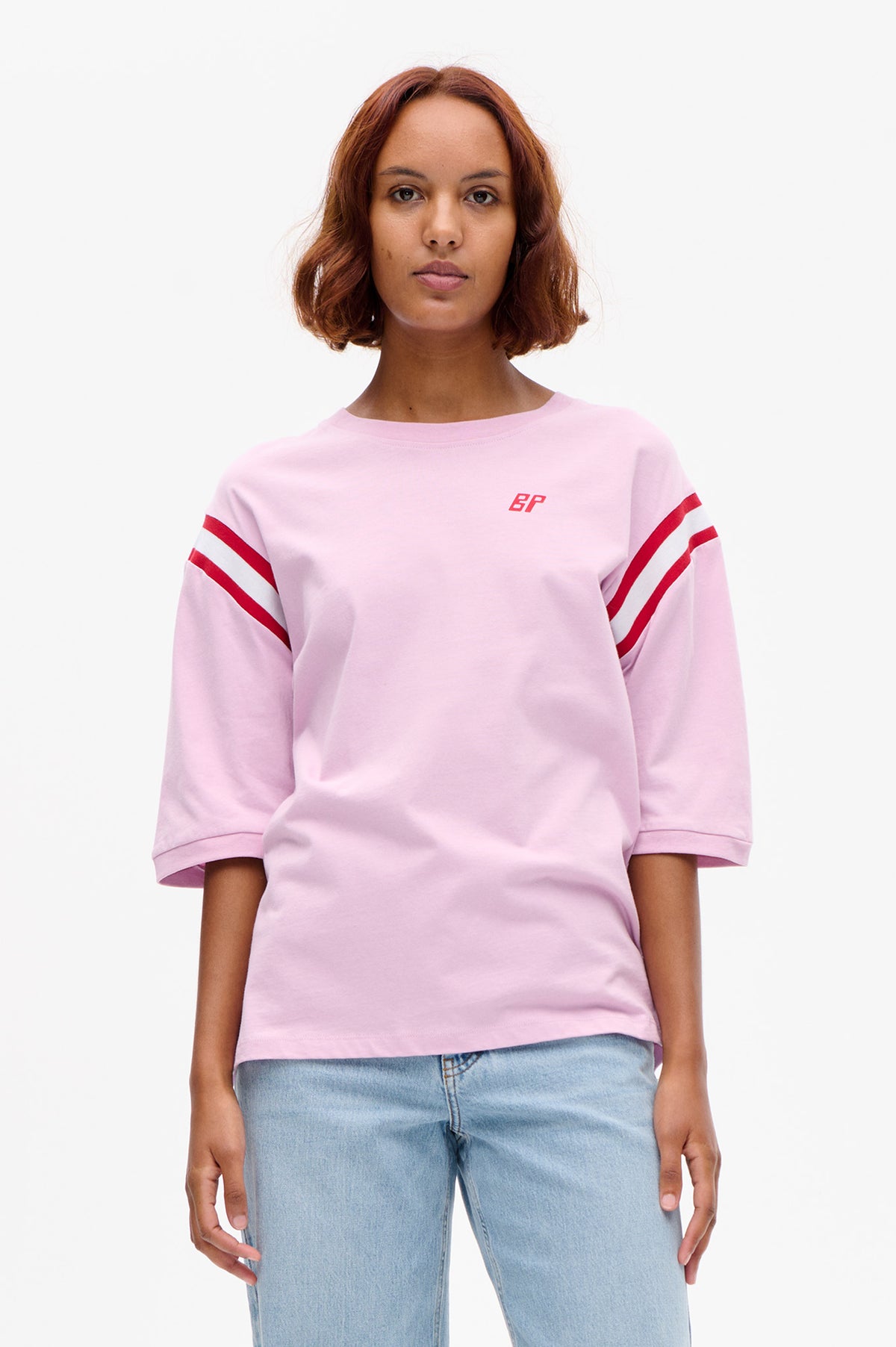 Front view of a pale pink short-sleeved sweatshirt with red and white sleeve stripes and a small red BP logo.