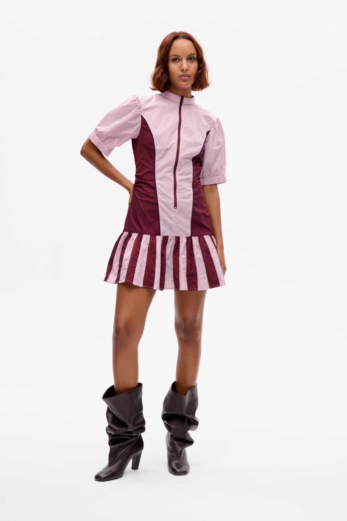 Front view of a colour-block mini dress with a pale pink zip-front panel and puff sleeves, burgundy bodice, and striped flared skirt.