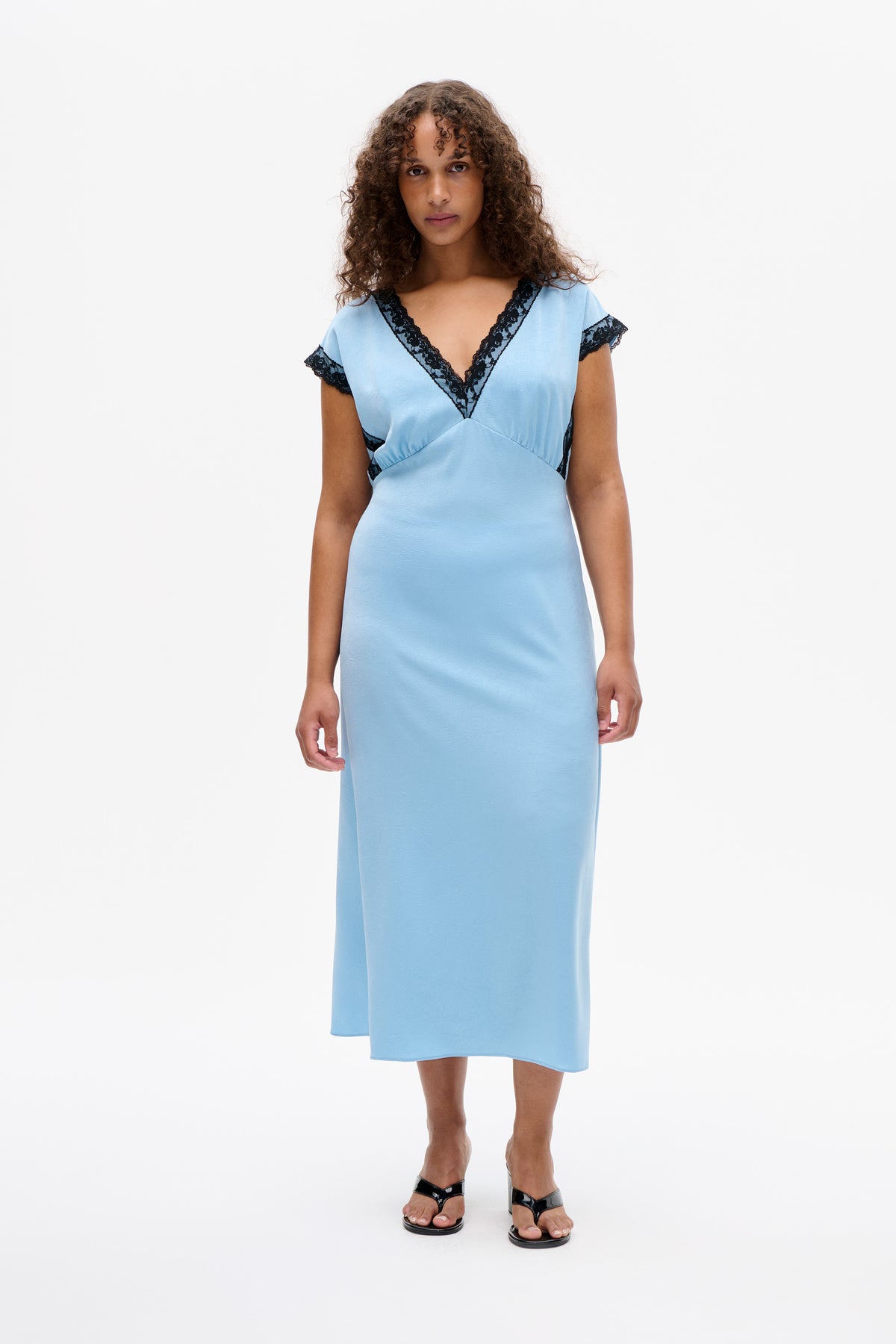 Front view of a light blue midi dress with a deep V-neck and short sleeves trimmed in black lace.