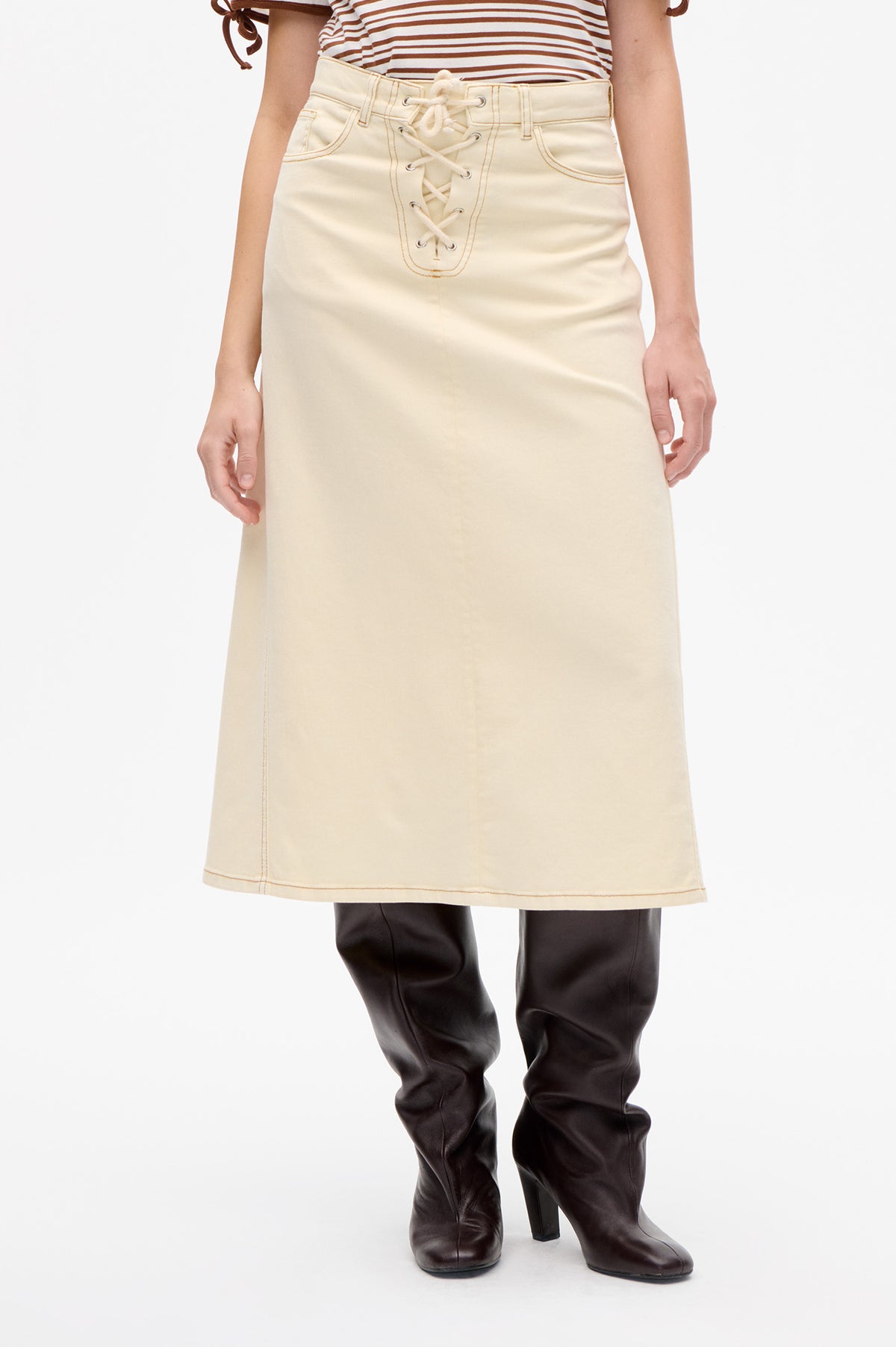 Front view of an ivory skirt with contrast stitching, front pockets and a lace-up waistband, styled with a brown-and-white striped top.