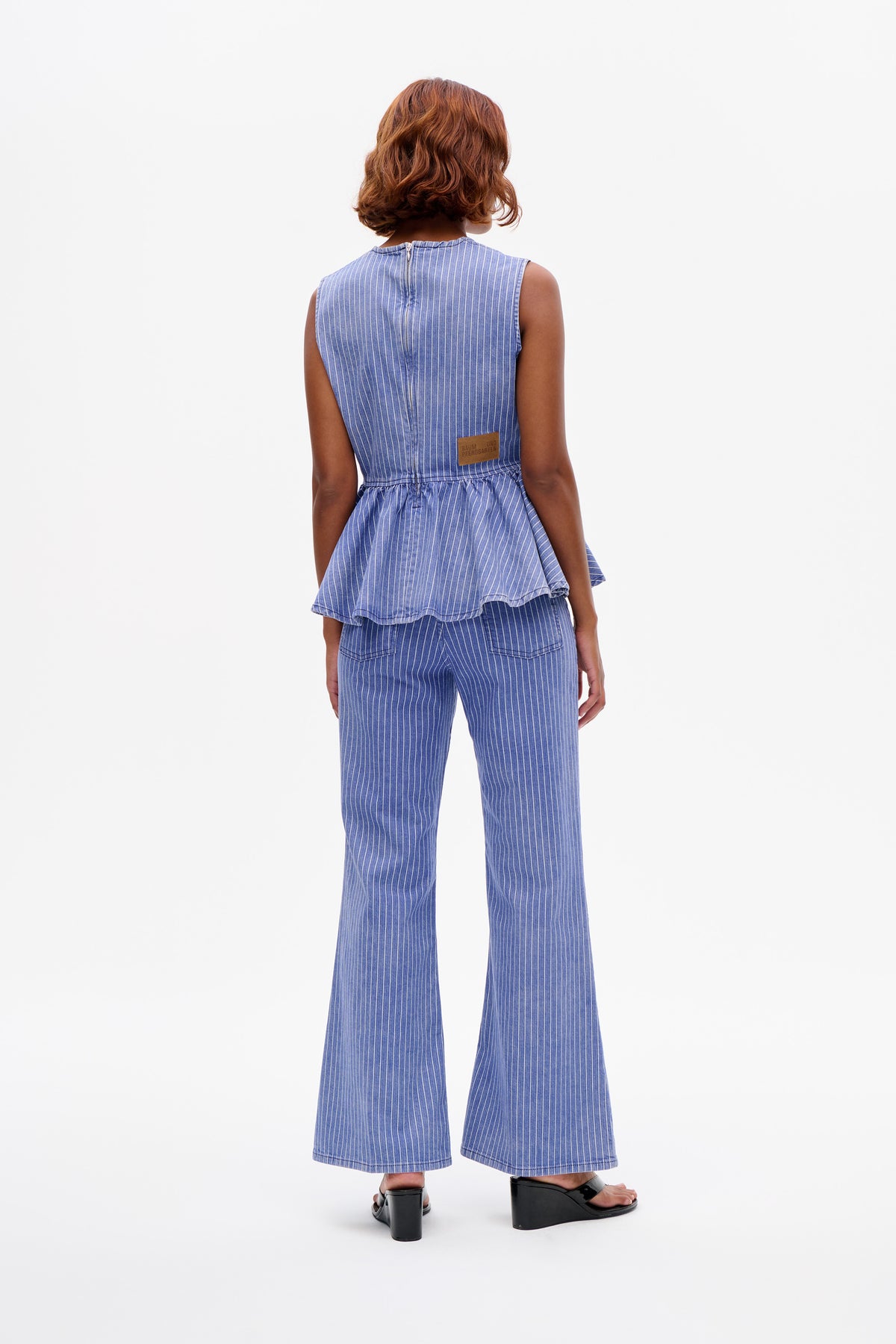 Back view of a blue pinstripe sleeveless peplum top with a center-back zipper and matching wide-leg trousers.