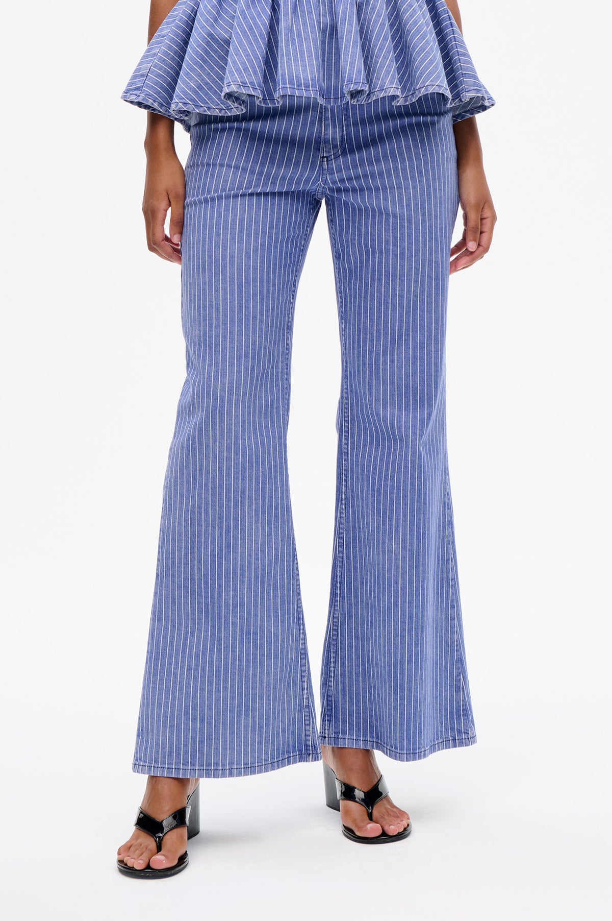 Détail avant d'une tenue bleu et blanc à fines rayures, manches superposées à volants et jambes larges raccourcies.