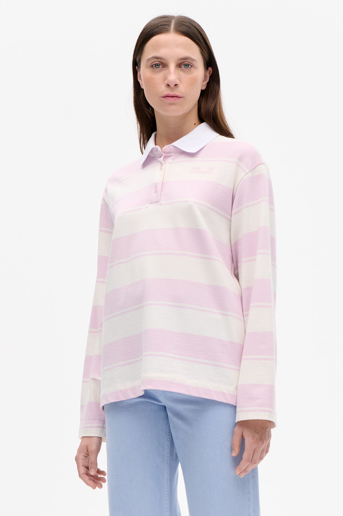 Front view of a model wearing a pink and ivory striped long-sleeve polo shirt with a white collar and small chest logo.