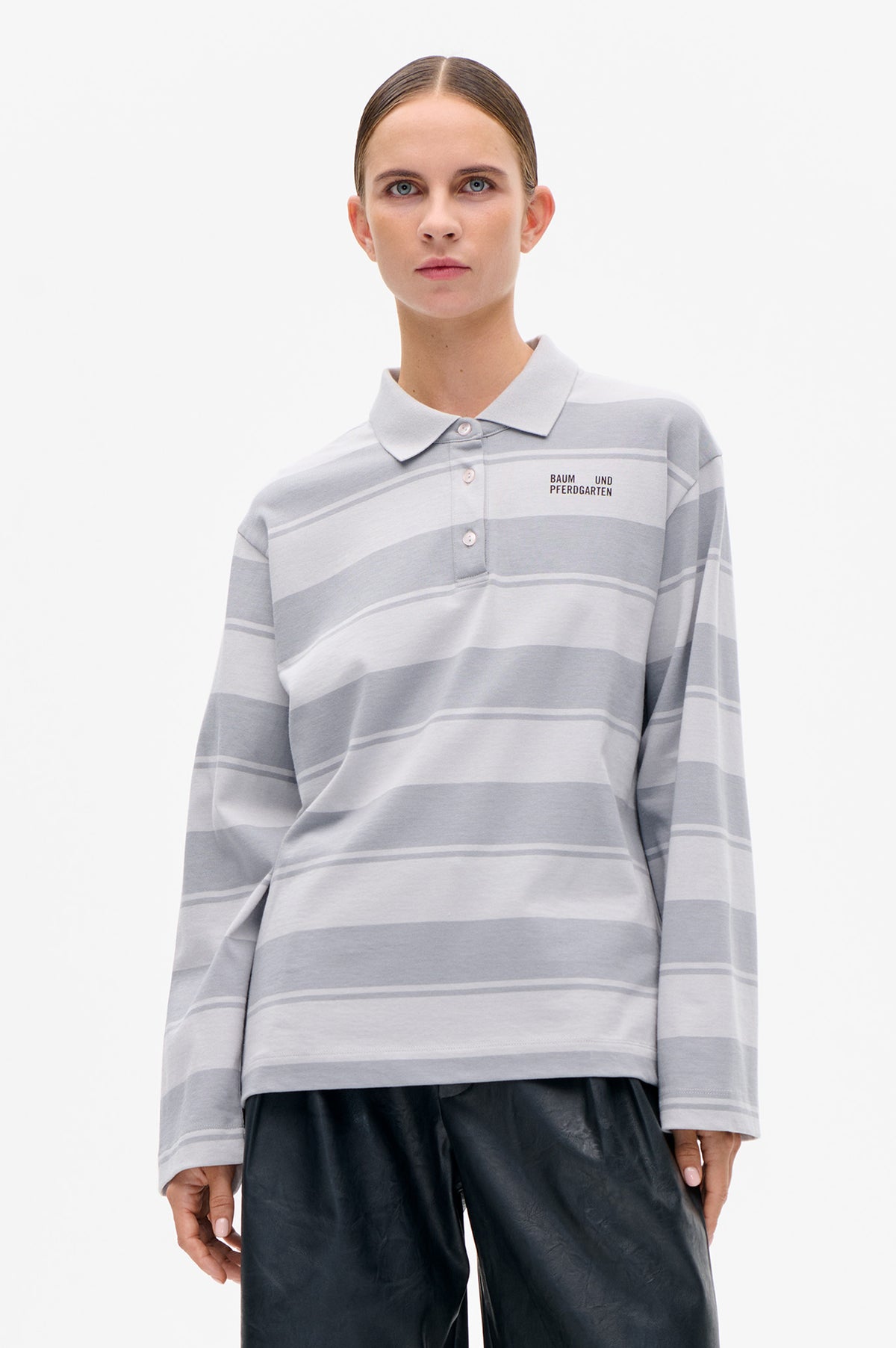 Front view of a model wearing a light grey striped long-sleeved polo shirt with a pointed collar, button placket and chest logo.