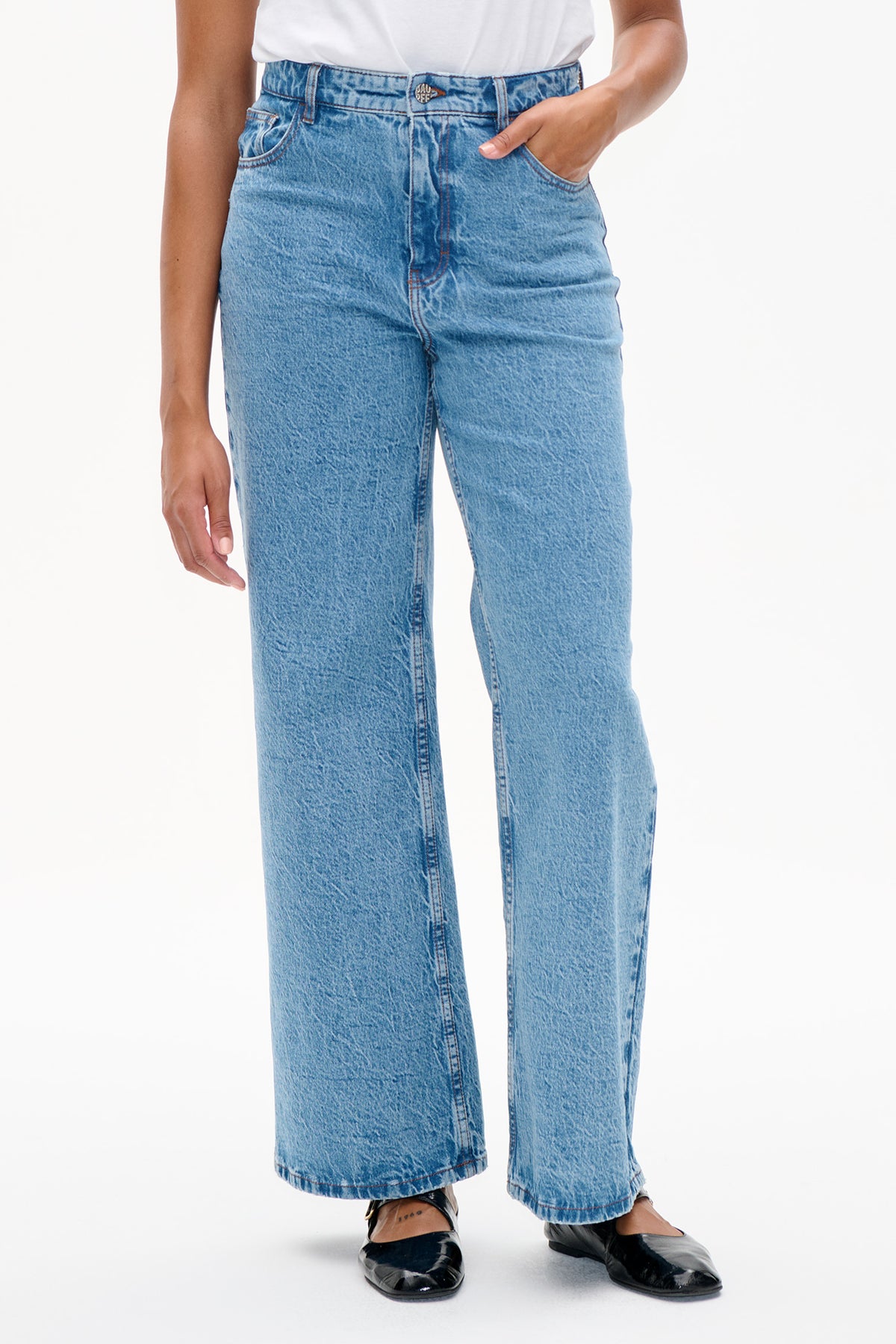 Detail van de voorkant van lichtblauwe acid-wash jeans met wijde pijpen, hoge taille, knoopsluiting en voorzakken.