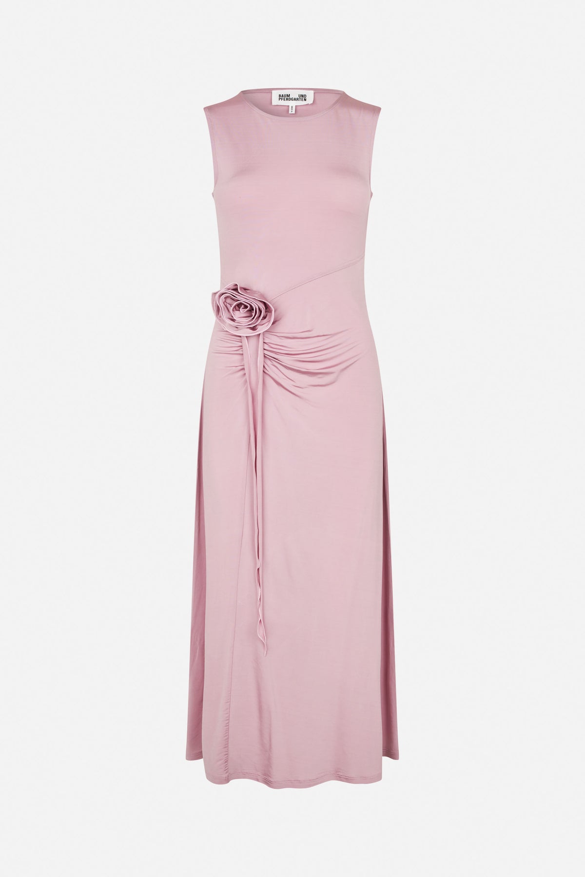 Front view of a dusty pink sleeveless dress with a round neckline, diagonal waist seam, gathered draping and a fabric rosette with long ties.
