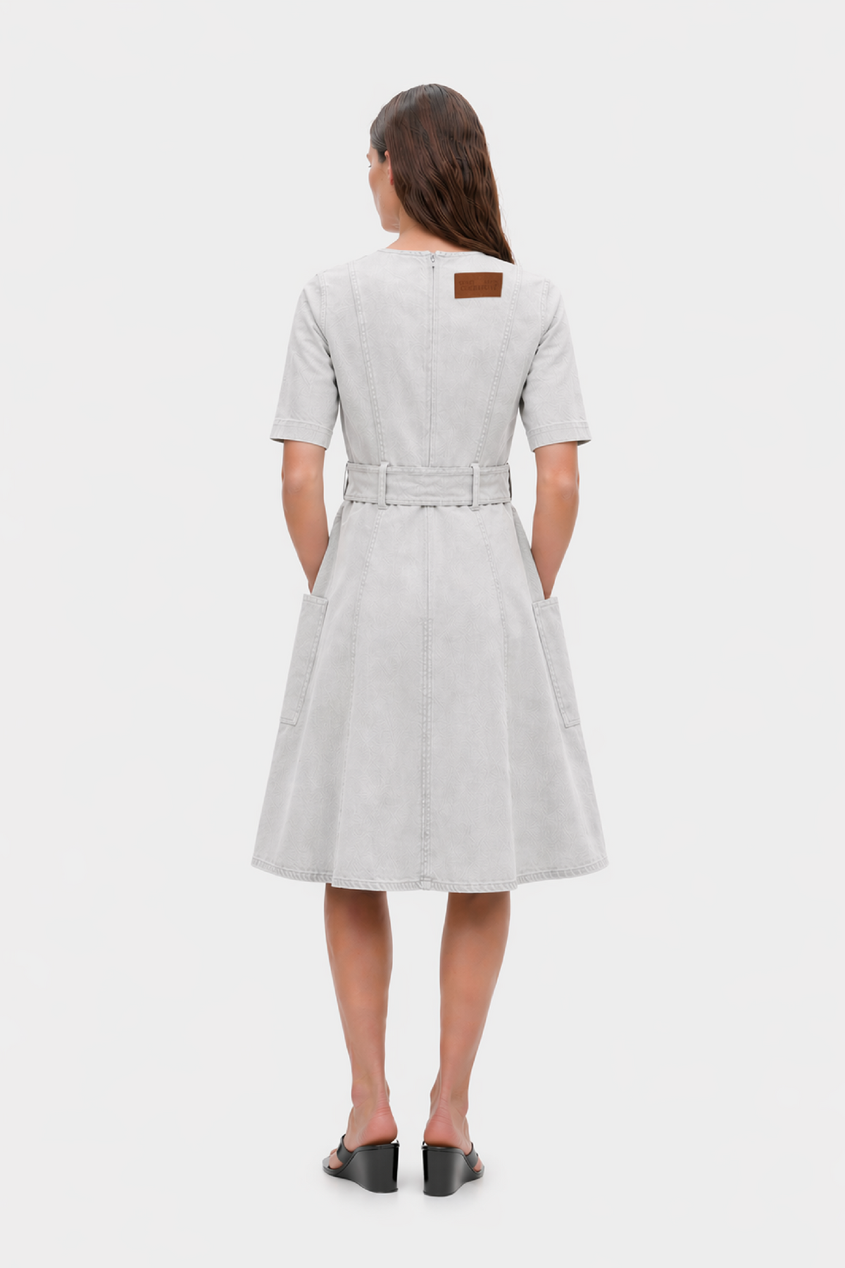 Back view of a pale grey short-sleeve midi dress with panel seams, a matching waist belt, side pockets and a brown label.