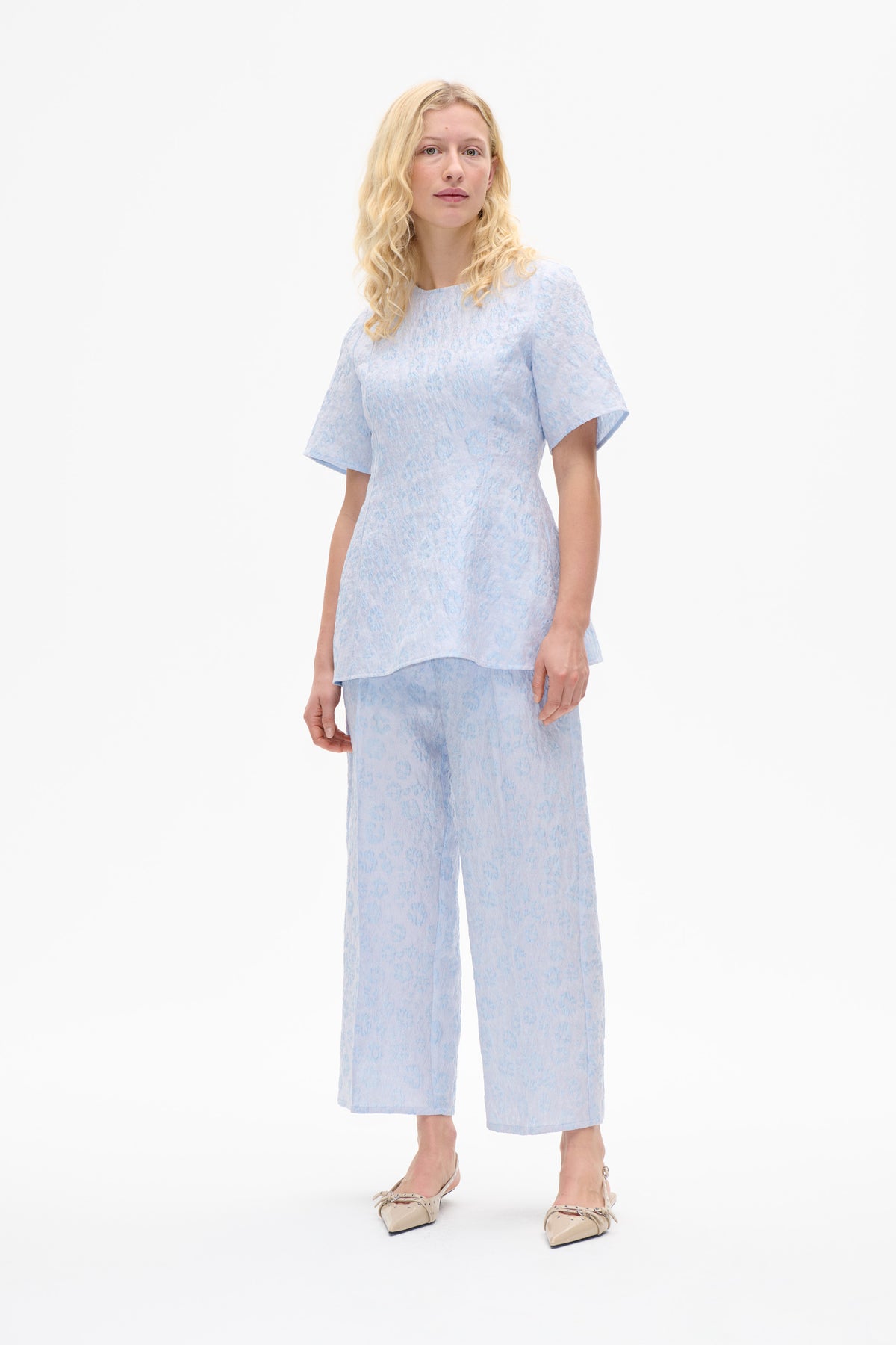 Mannequin portant un haut à manches courtes bleu pâle à imprimé floral et un pantalon large raccourci assorti, vu de face.