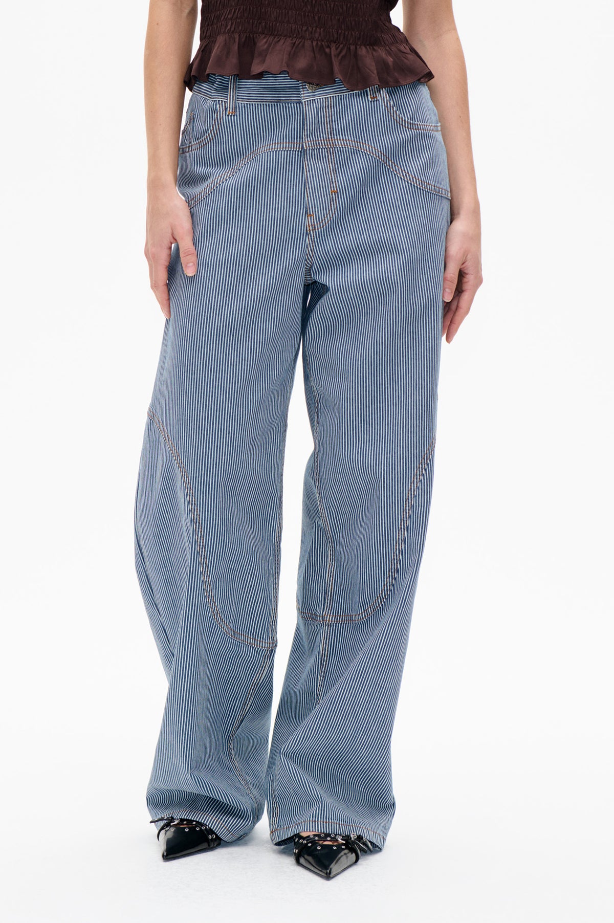 Front detail of blue-and-white pinstripe trousers with curved pockets and contrasting orange stitching