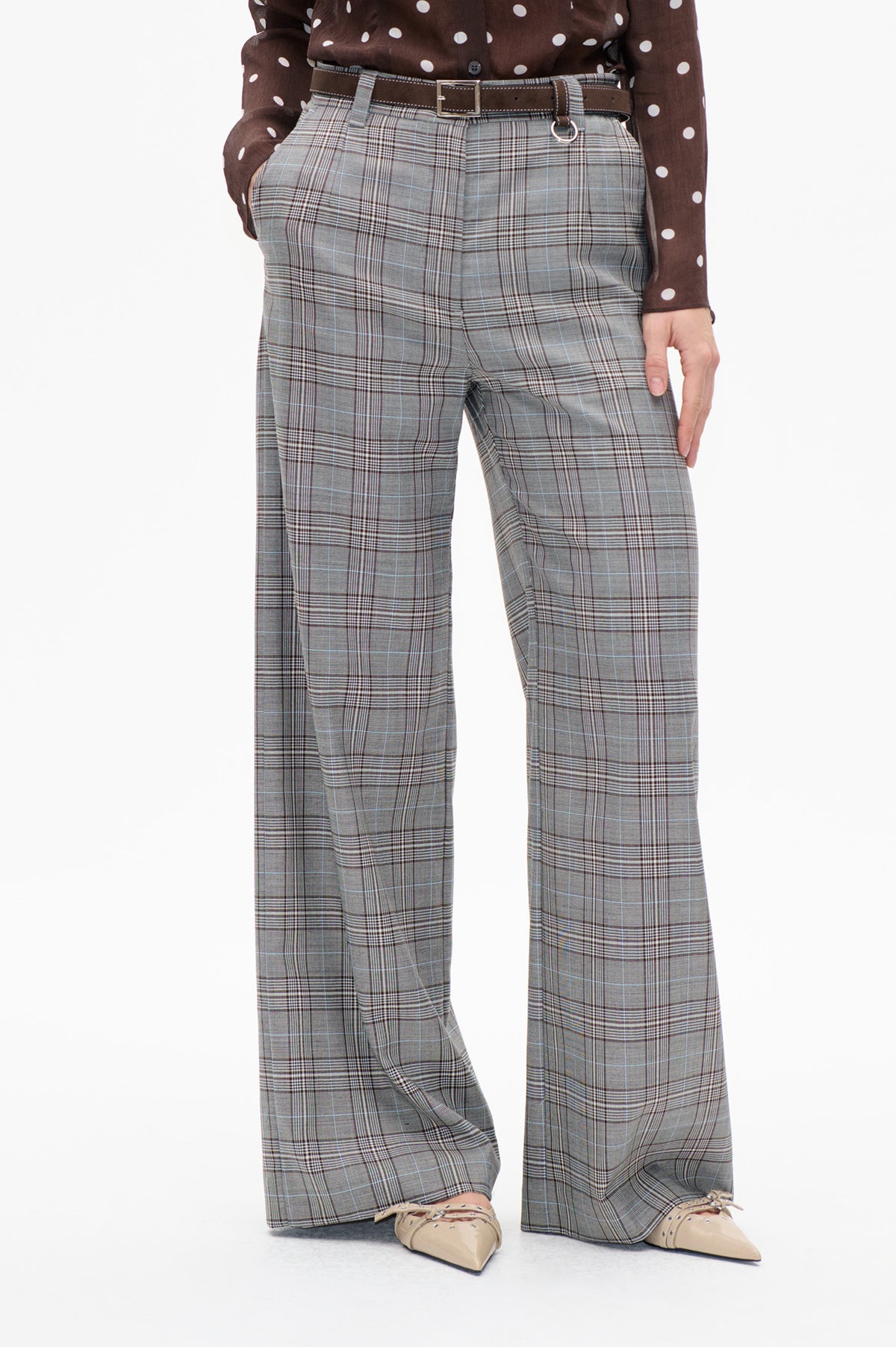 Front detail of grey plaid wide-leg trousers with pleats, styled with a dark brown belt and a brown polka-dot shirt.