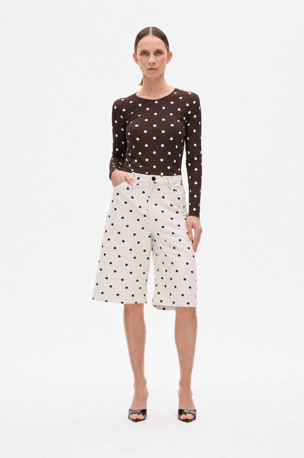 Front view of a dark brown long-sleeve top with white polka dots paired with ivory knee-length shorts with dark dots.