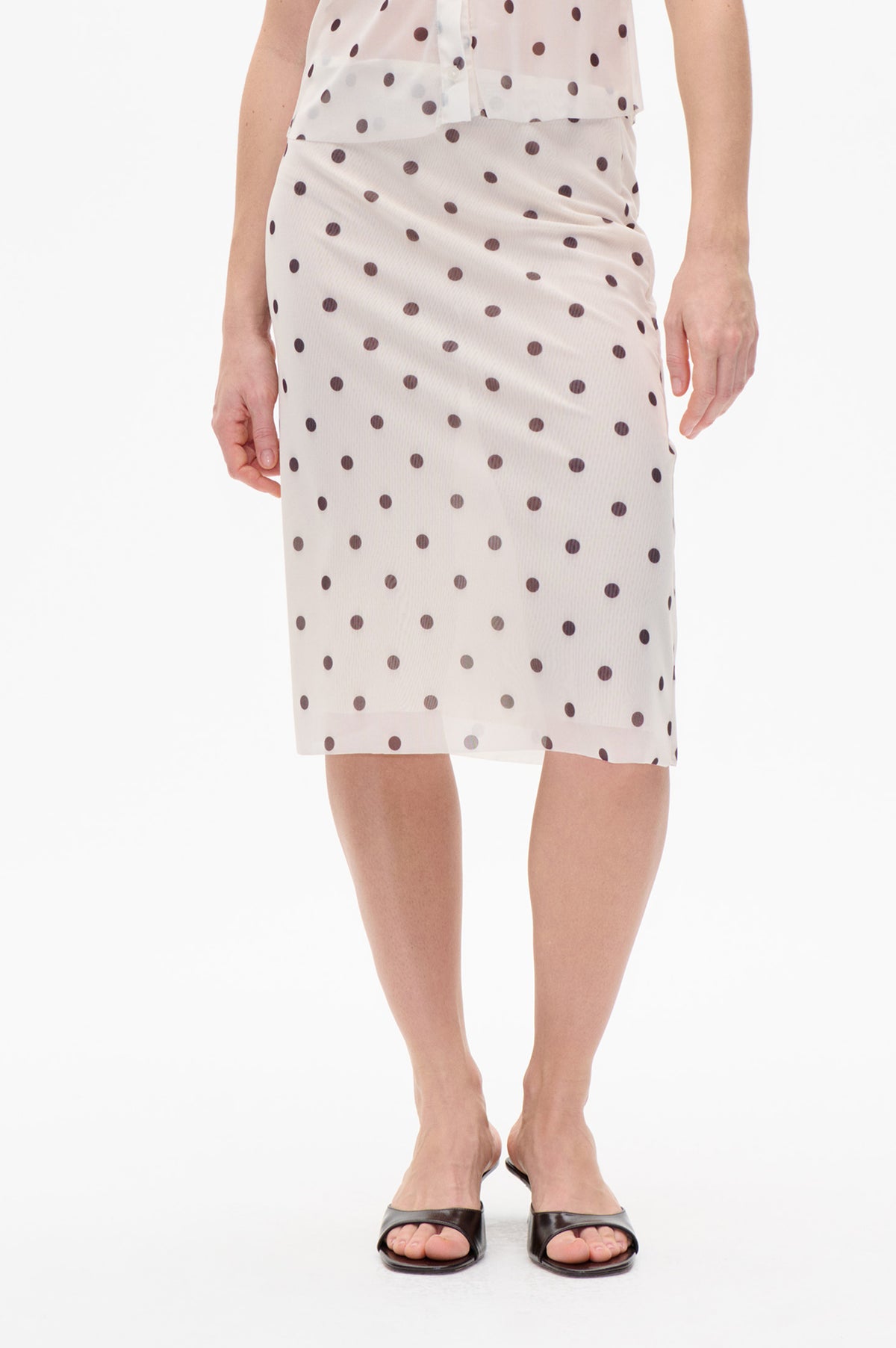 Front detail of a cream knee-length skirt with dark brown polka dots and a softly gathered waist