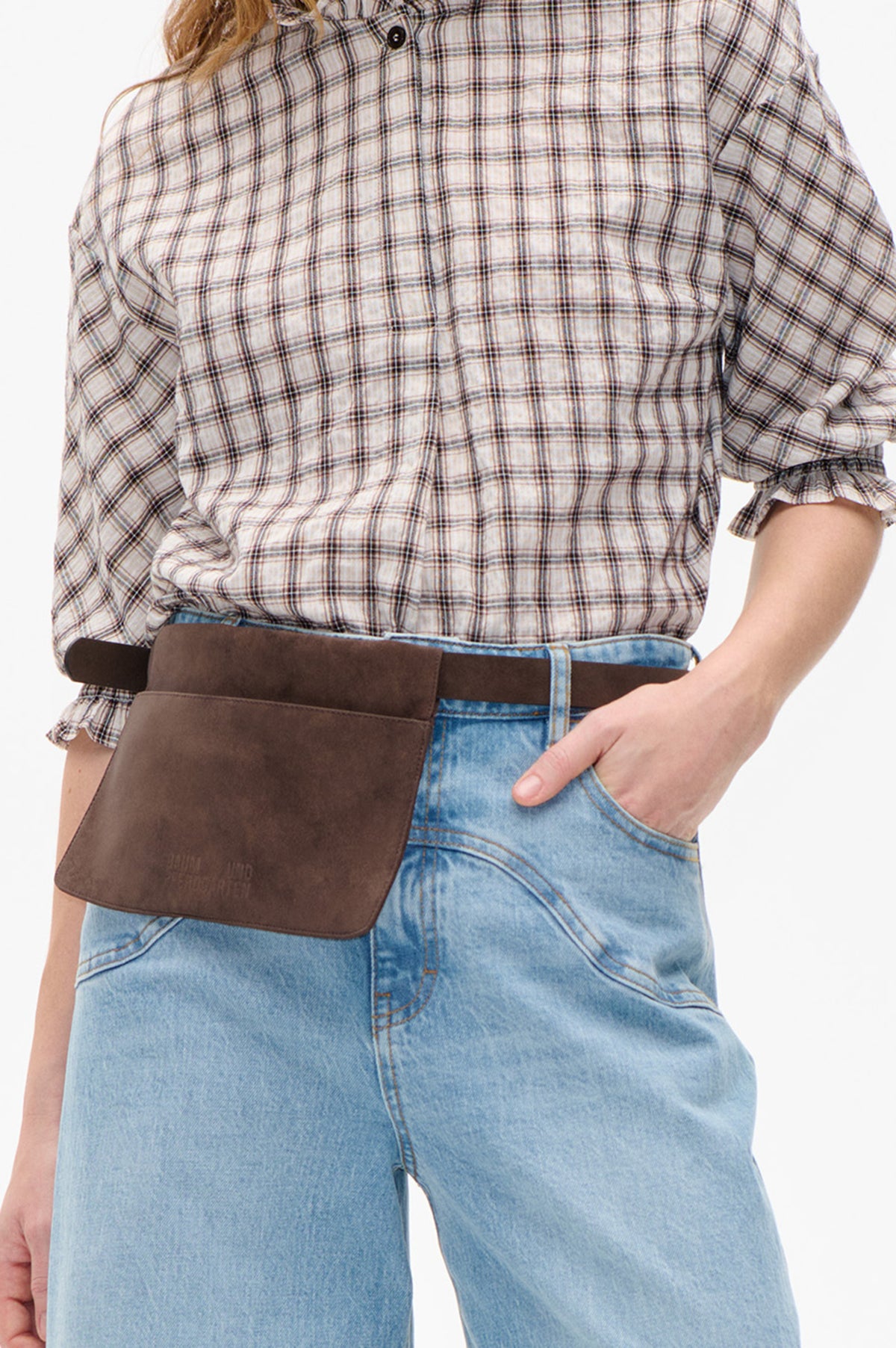 Close front view of a cream plaid blouse with dark brown lines, a button front, gathered waist and ruffled short sleeves