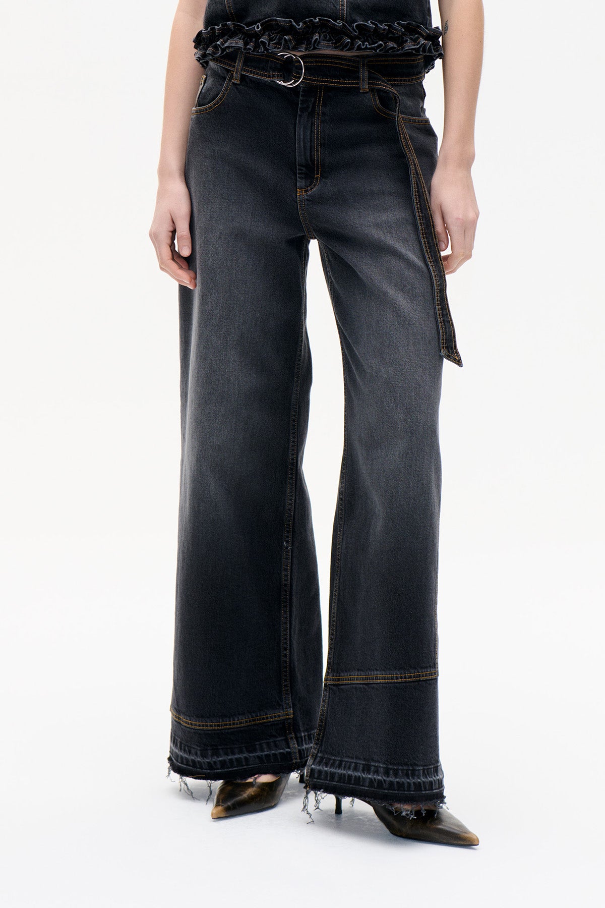 Front view of charcoal wide-leg jeans with contrast stitching, a metal ring at the waist, and frayed hems.