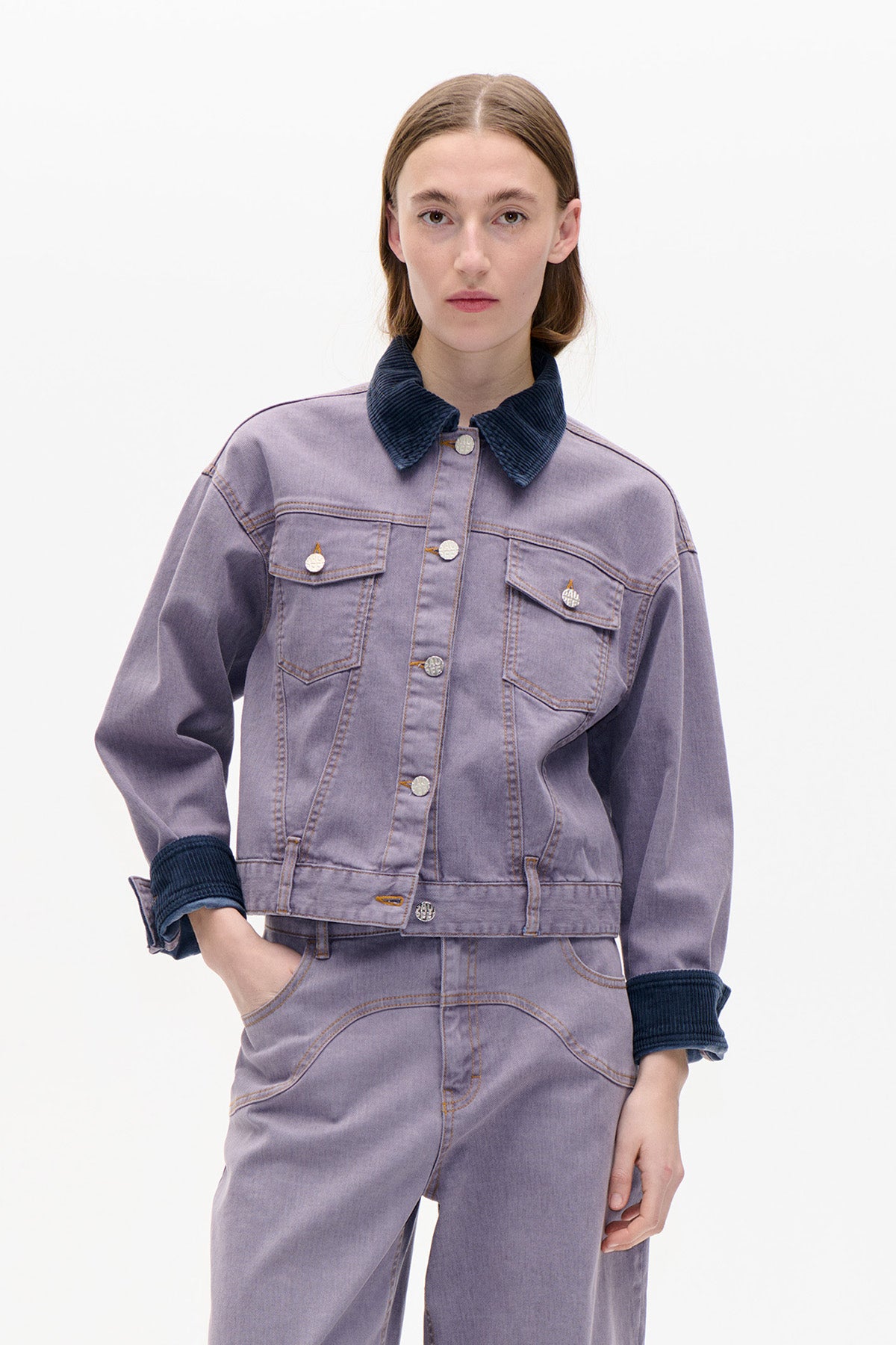 Front view of a lavender denim jacket with a dark navy corduroy collar and cuffs, paired with matching trousers.