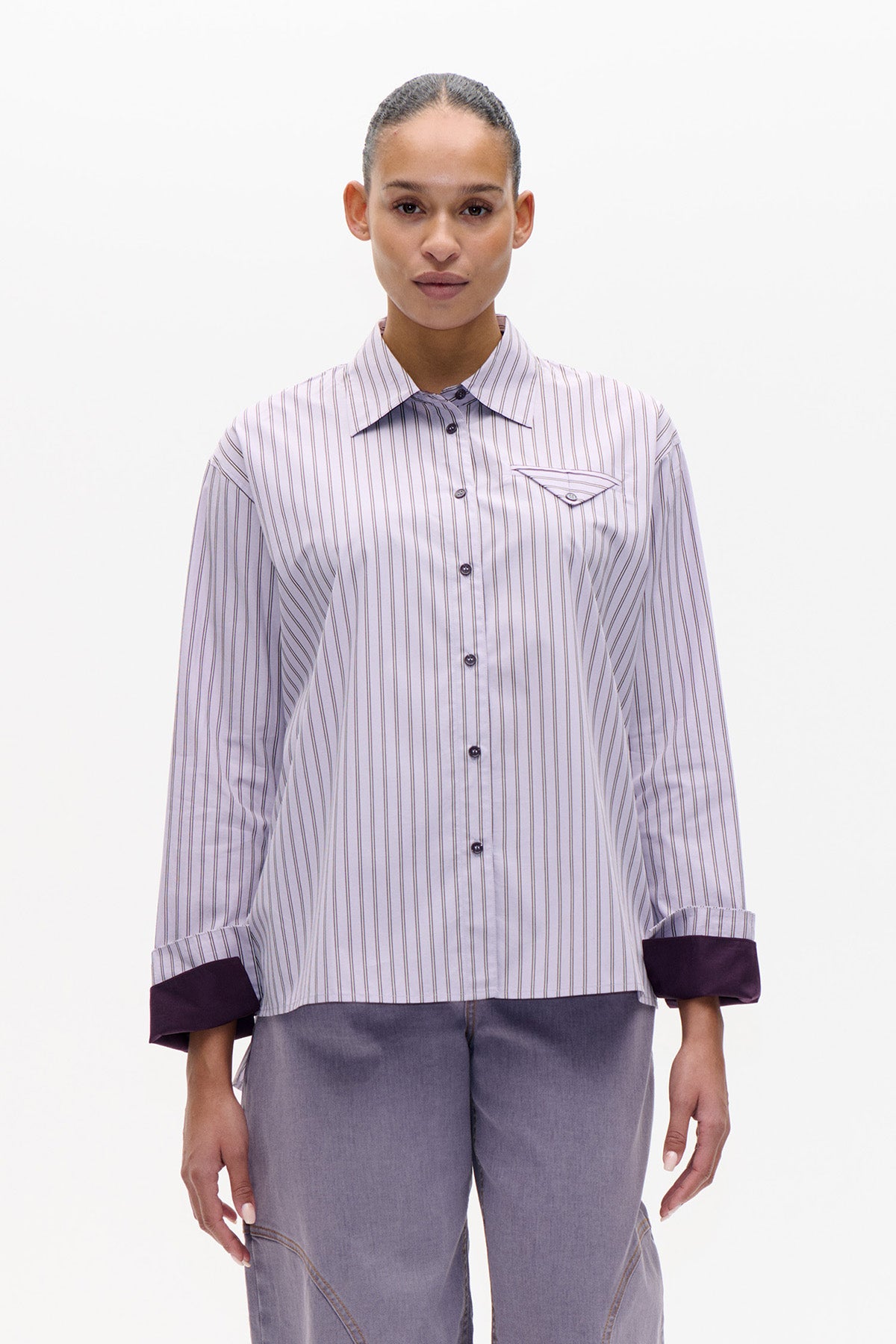 Front view of a pale lilac button-up shirt with fine vertical stripes, a pointed collar, chest pocket and dark contrast cuffs.