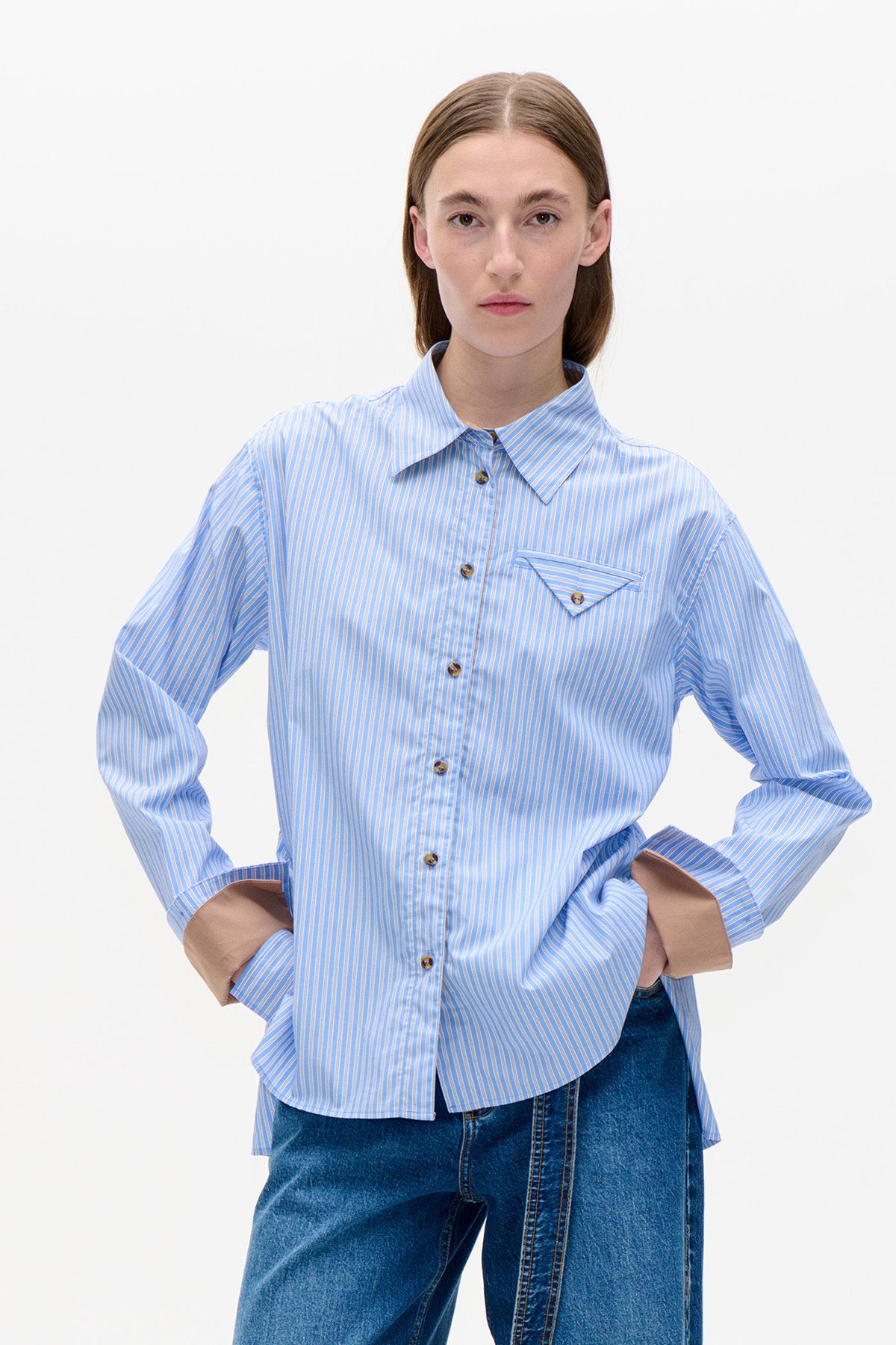Front view of a light blue and white striped button-front shirt with a pointed collar, chest pocket and contrasting tan cuffs.
